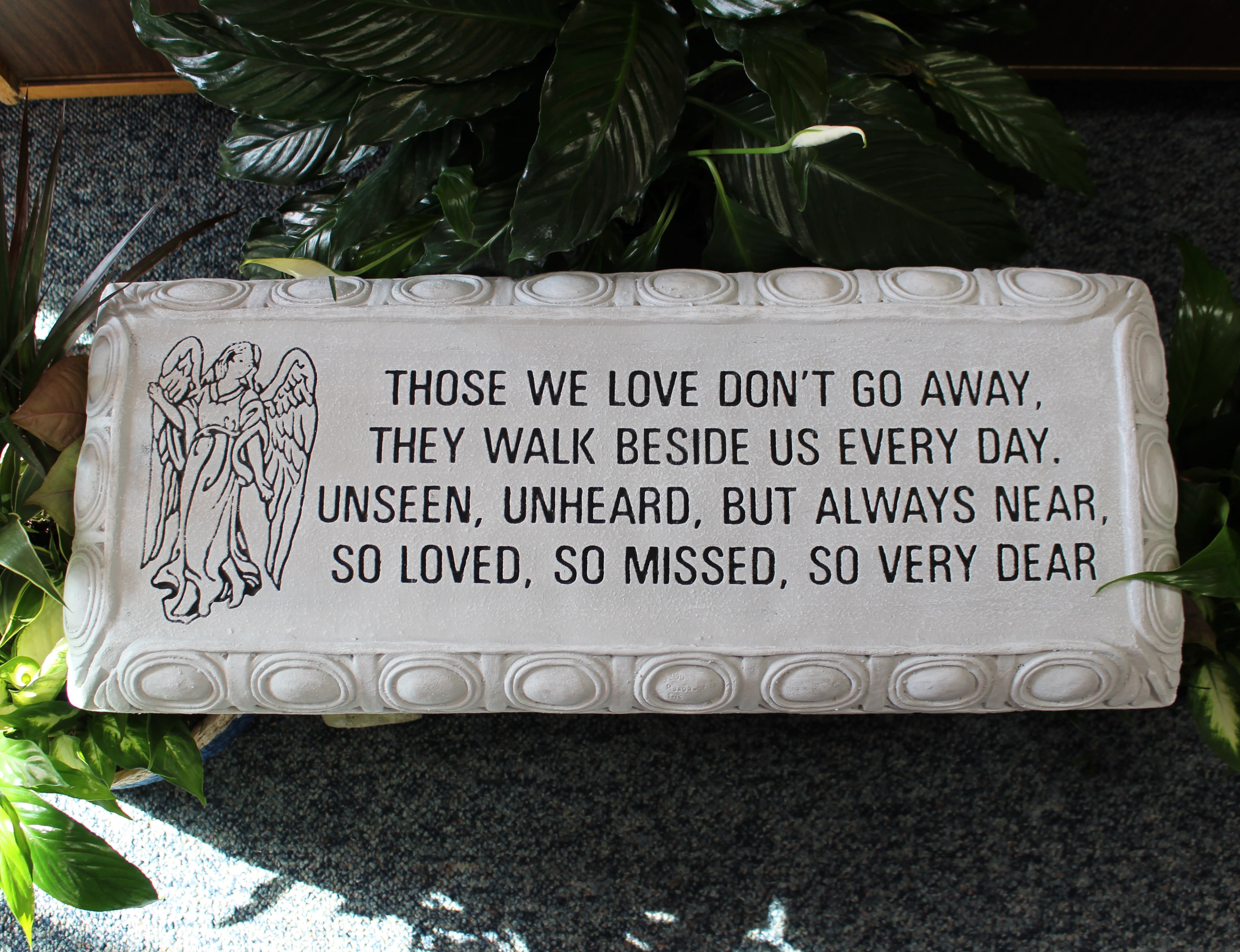 Memorial plaque with an angel and sympathy verse surrounded by plants