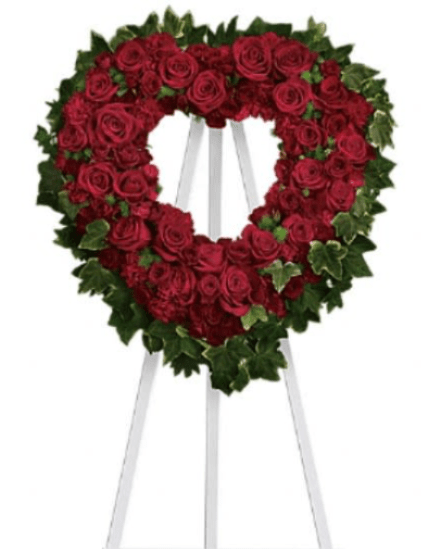 Heart-shaped red rose wreath on a white easel