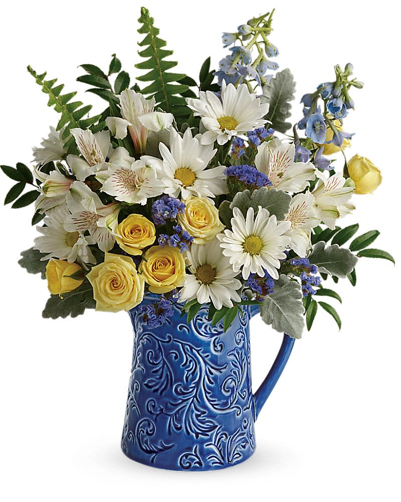 Bouquet of white daisies and yellow roses in a blue ceramic pitcher