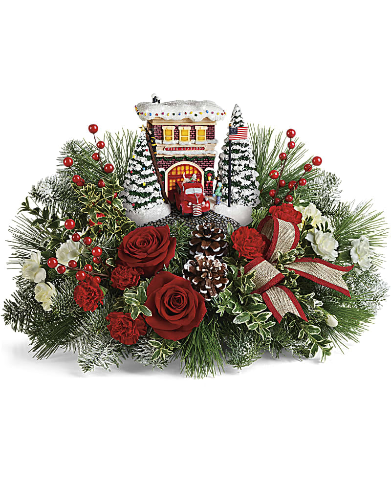 Christmas arrangement with red roses, pinecones, and a miniature snowy house
