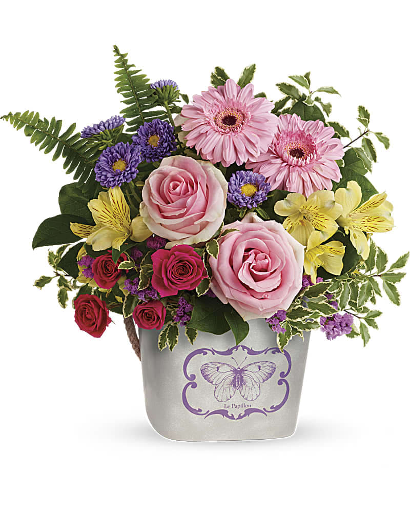 Mixed bouquet of pink roses, gerbera daisies, and purple flowers in a butterfly vase
