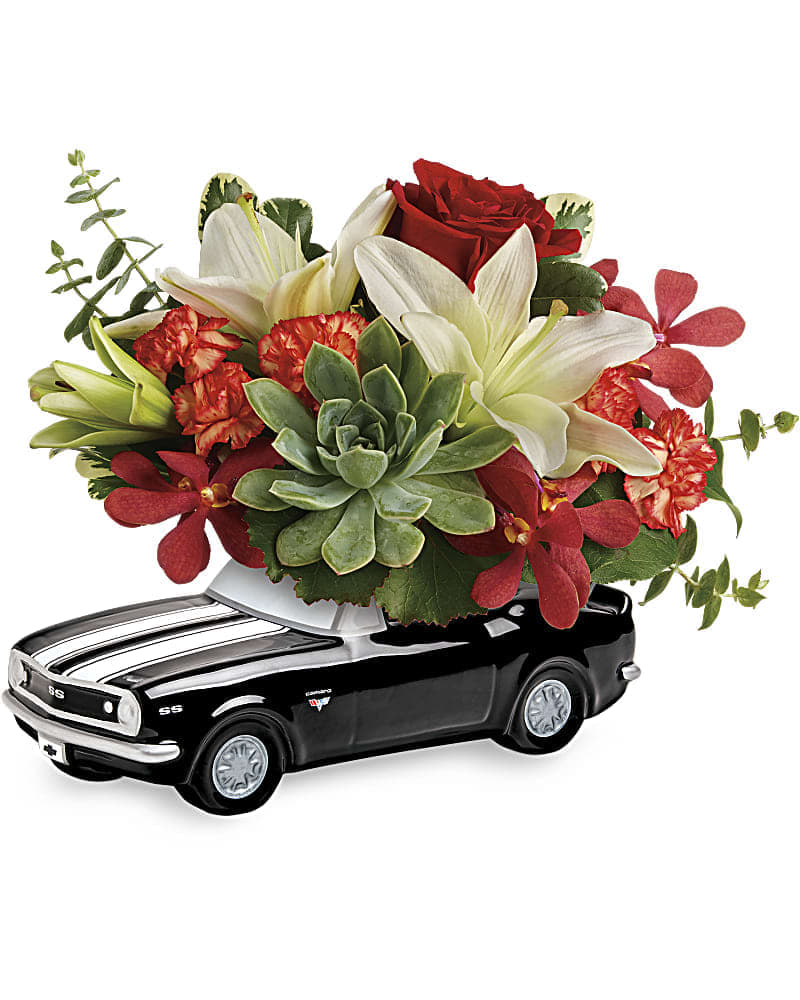 Flower arrangement in a black toy car container with red and white blooms