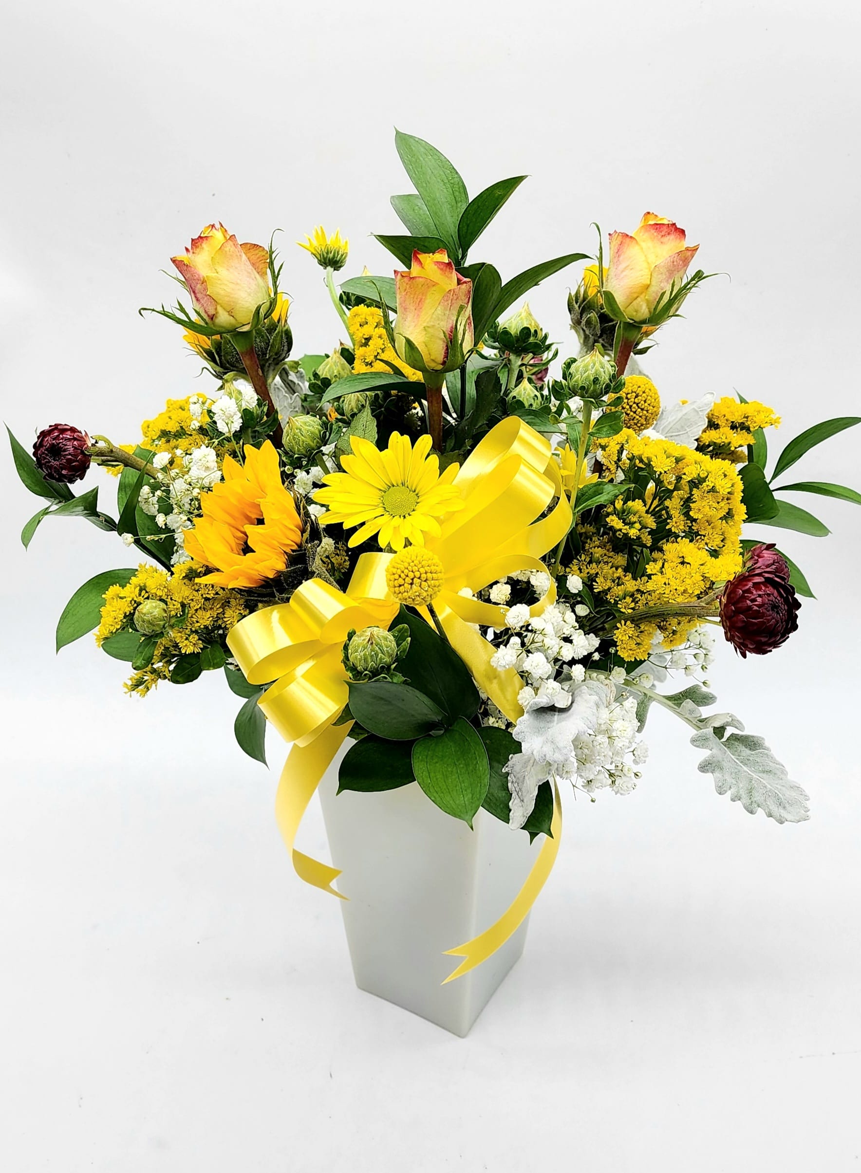 Yellow and white floral arrangement in a white vase with a yellow ribbon