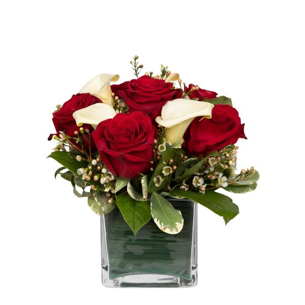 Red roses and white calla lilies in a square glass vase