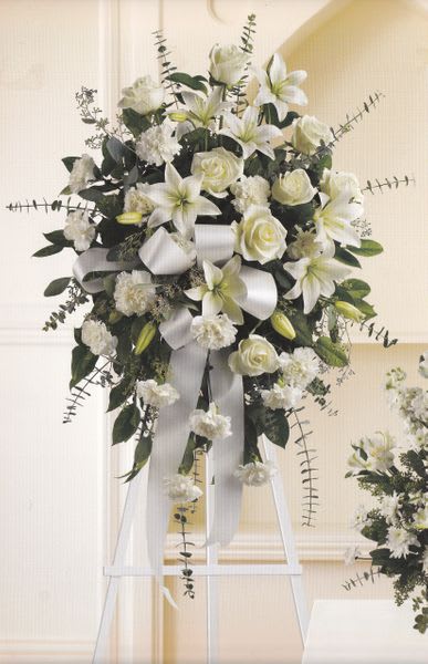 White floral standing spray on an easel with ribbon streamers