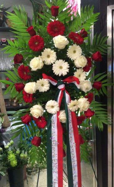 Tall standing floral spray with red and white flowers and ribbon streamers