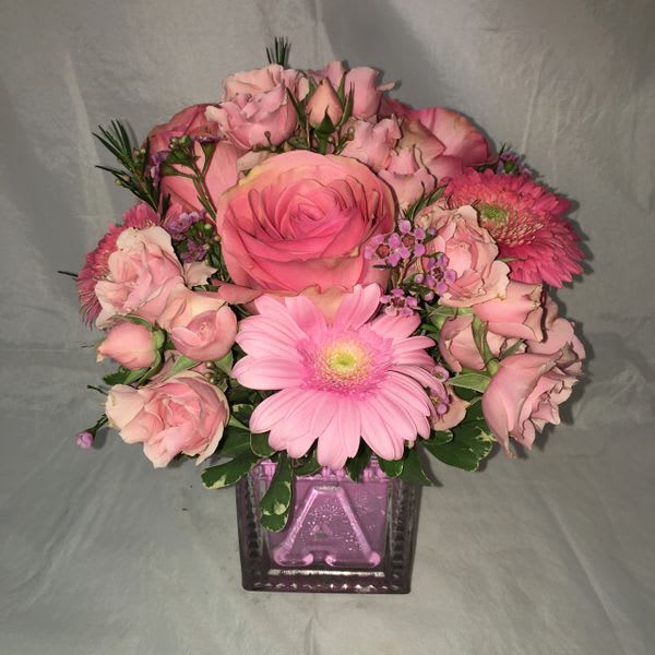 Pink rose and gerbera daisy bouquet in a purple glass vase