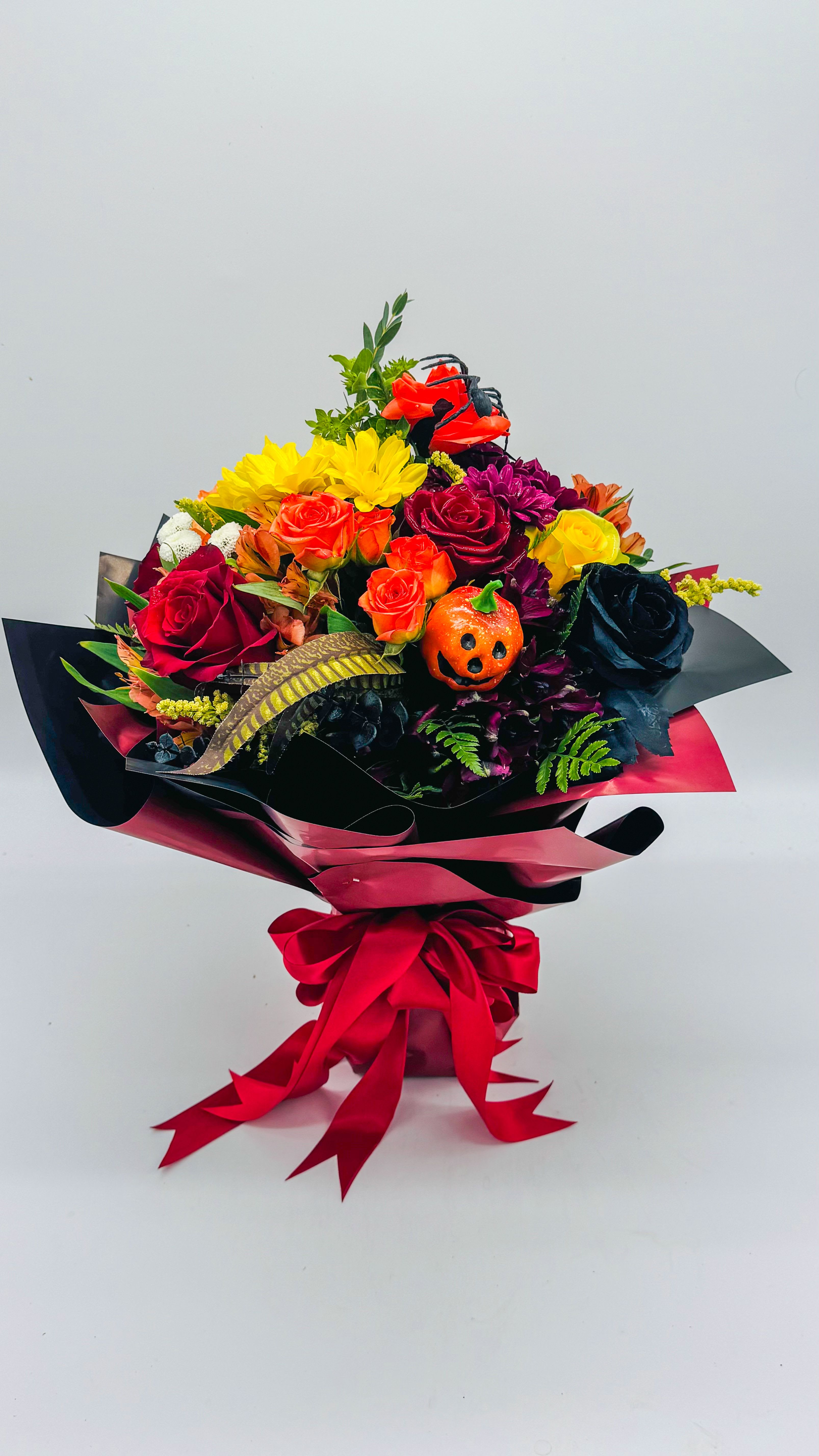  Halloween vase wrap  -   A fall-colored bouquet housed in a sleek vase, wrapped in waterproof paper to achieve a modern, crisp edge. The arrangement blends warm amber, burgundy, and orange blooms with dark accents for a subtly Halloween-inspired vibe—perfect for contemporary display.