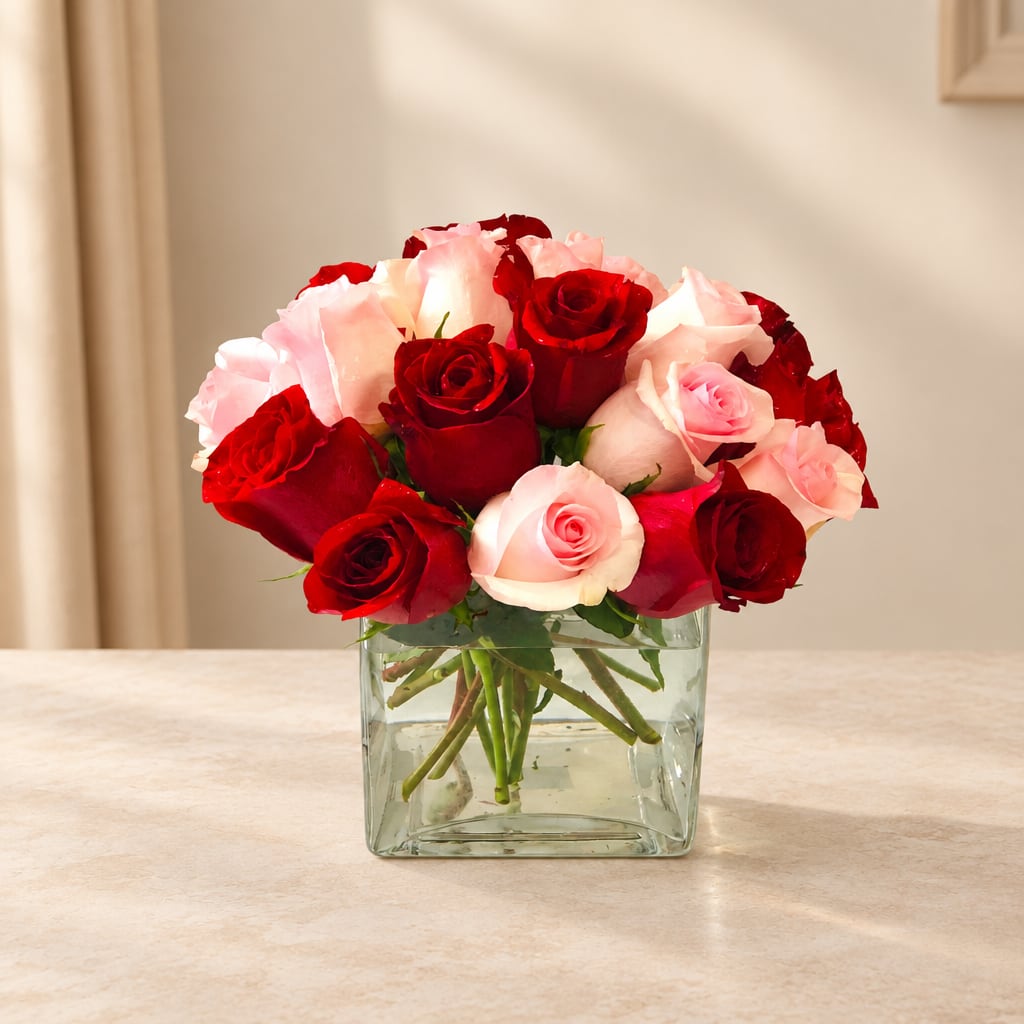 Red and pink roses arranged in a clear square glass vase