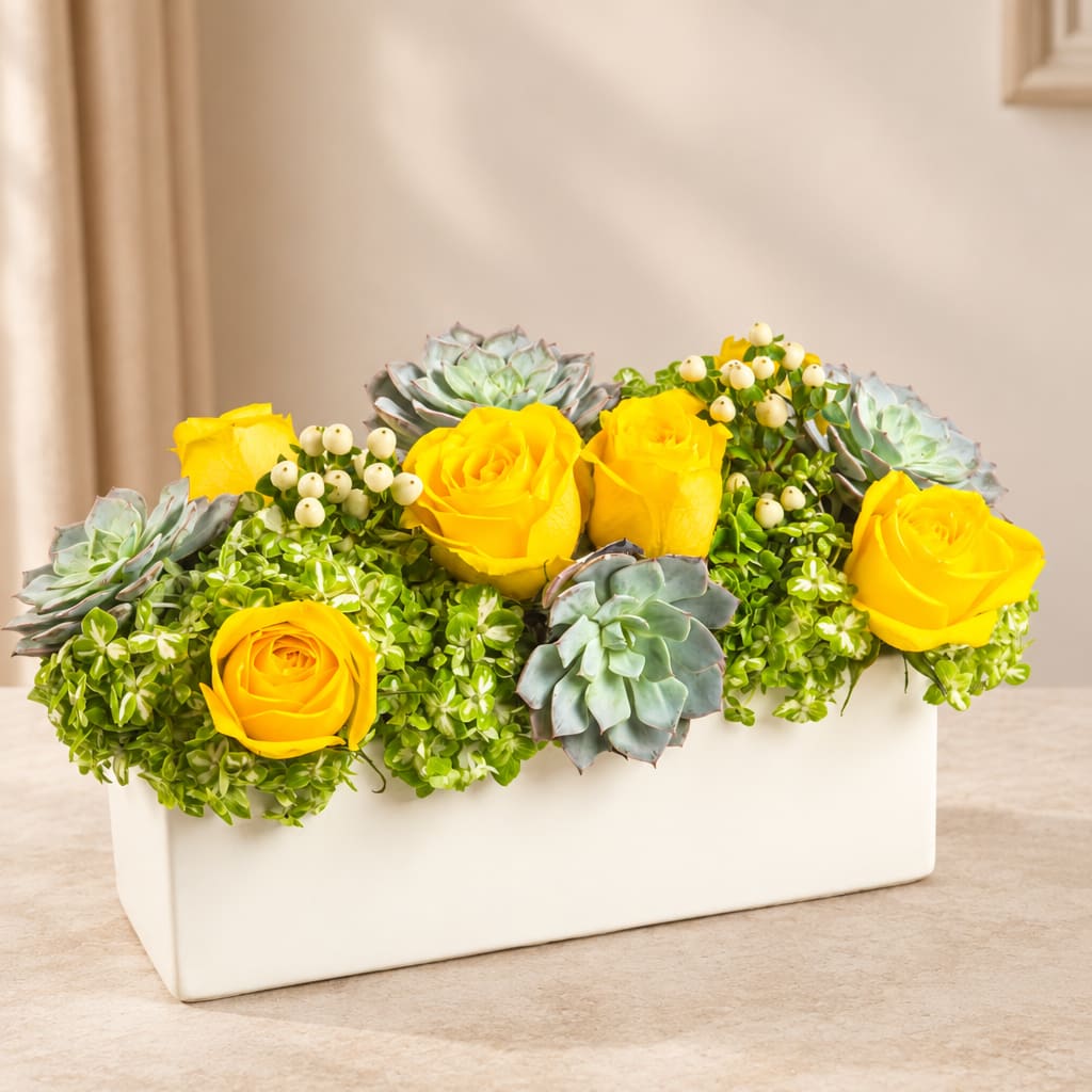 Yellow roses and succulents arranged in a white rectangular vase