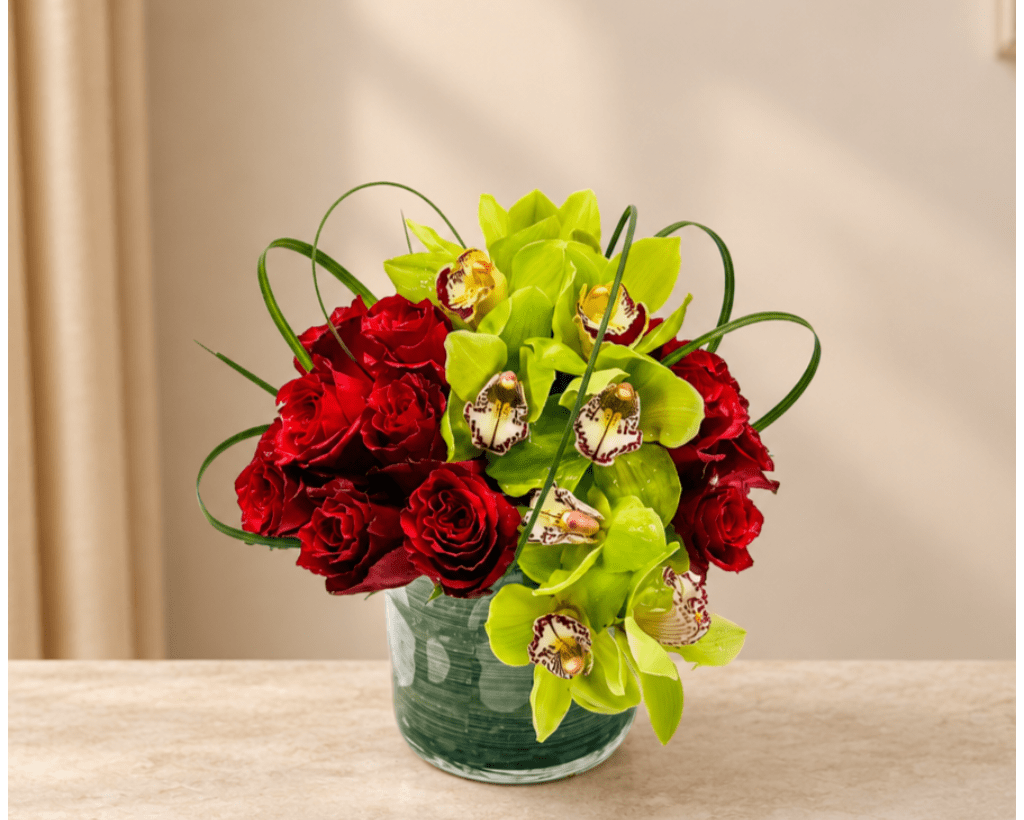 Red roses and green orchids in a glass vase