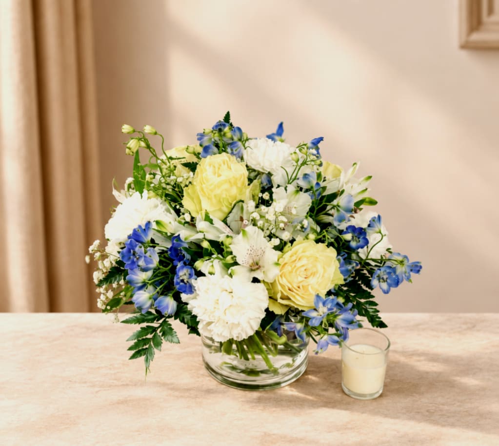 Bouquet of yellow, white, and blue flowers in a glass bowl vase