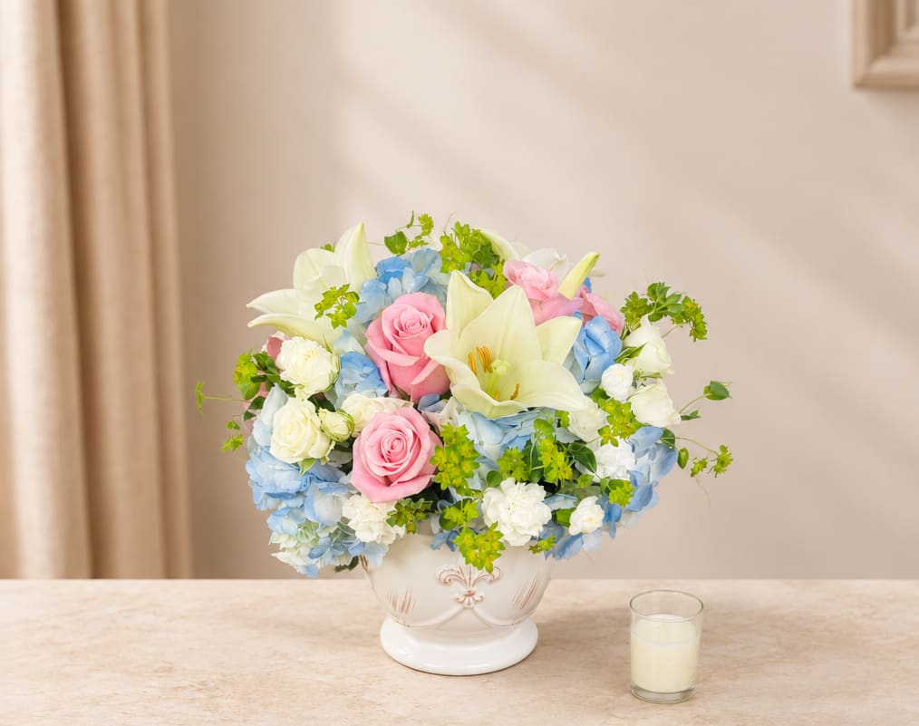 Pastel bouquet of roses, lilies, and hydrangeas in a white vase