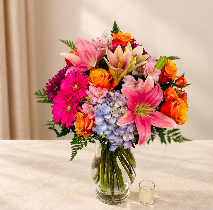 Colorful bouquet of lilies, roses, gerberas, and hydrangea in a glass vase