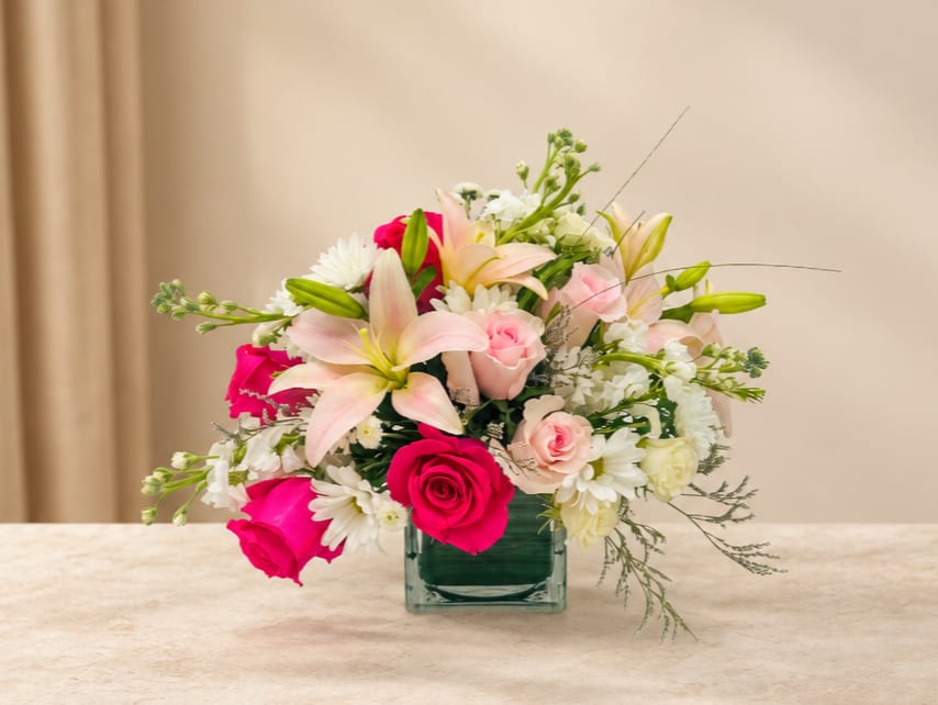 Pink and white mixed flower arrangement in a square glass vase