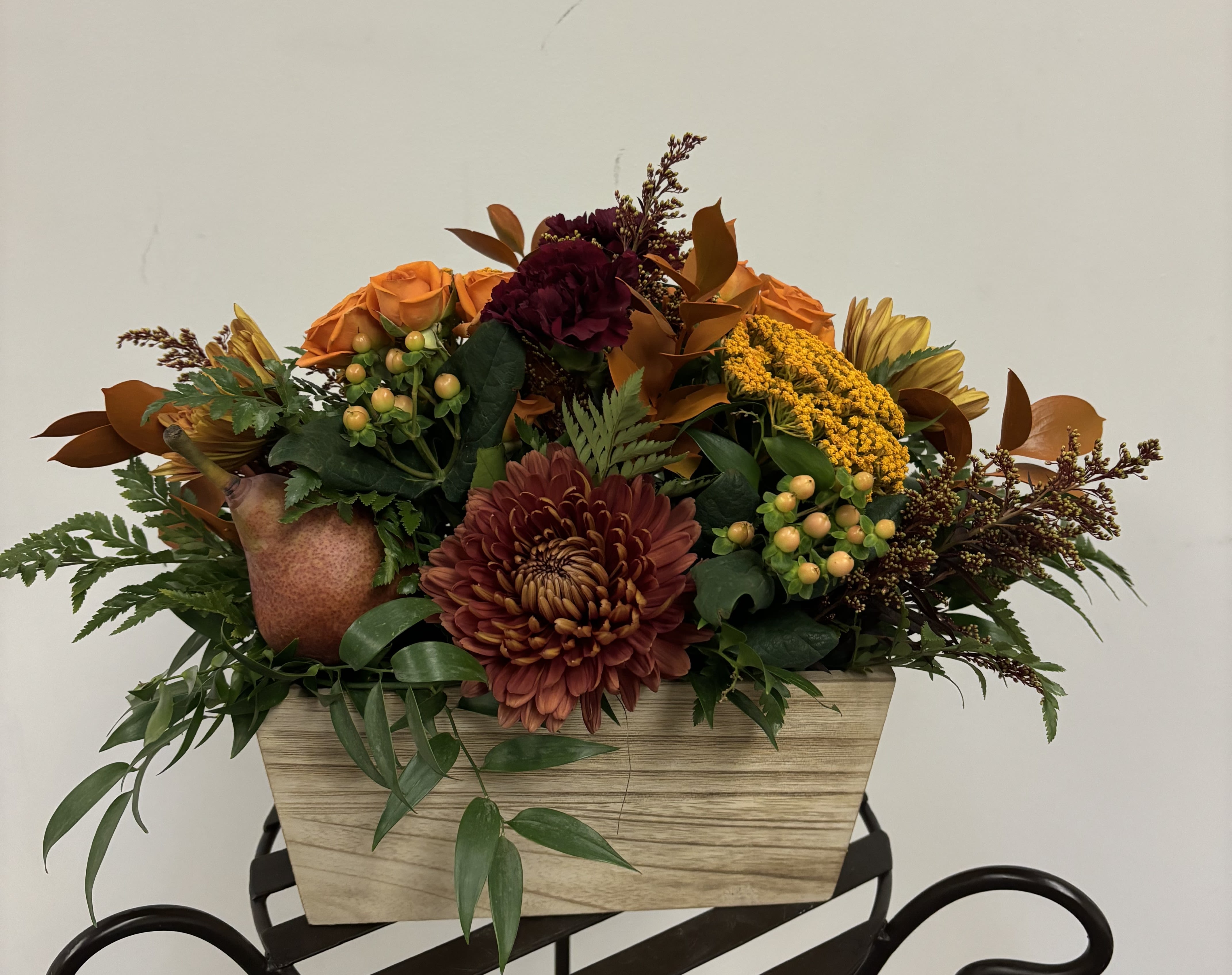 Autumn floral arrangement in a wood-look rectangular container with orange and burgundy blooms