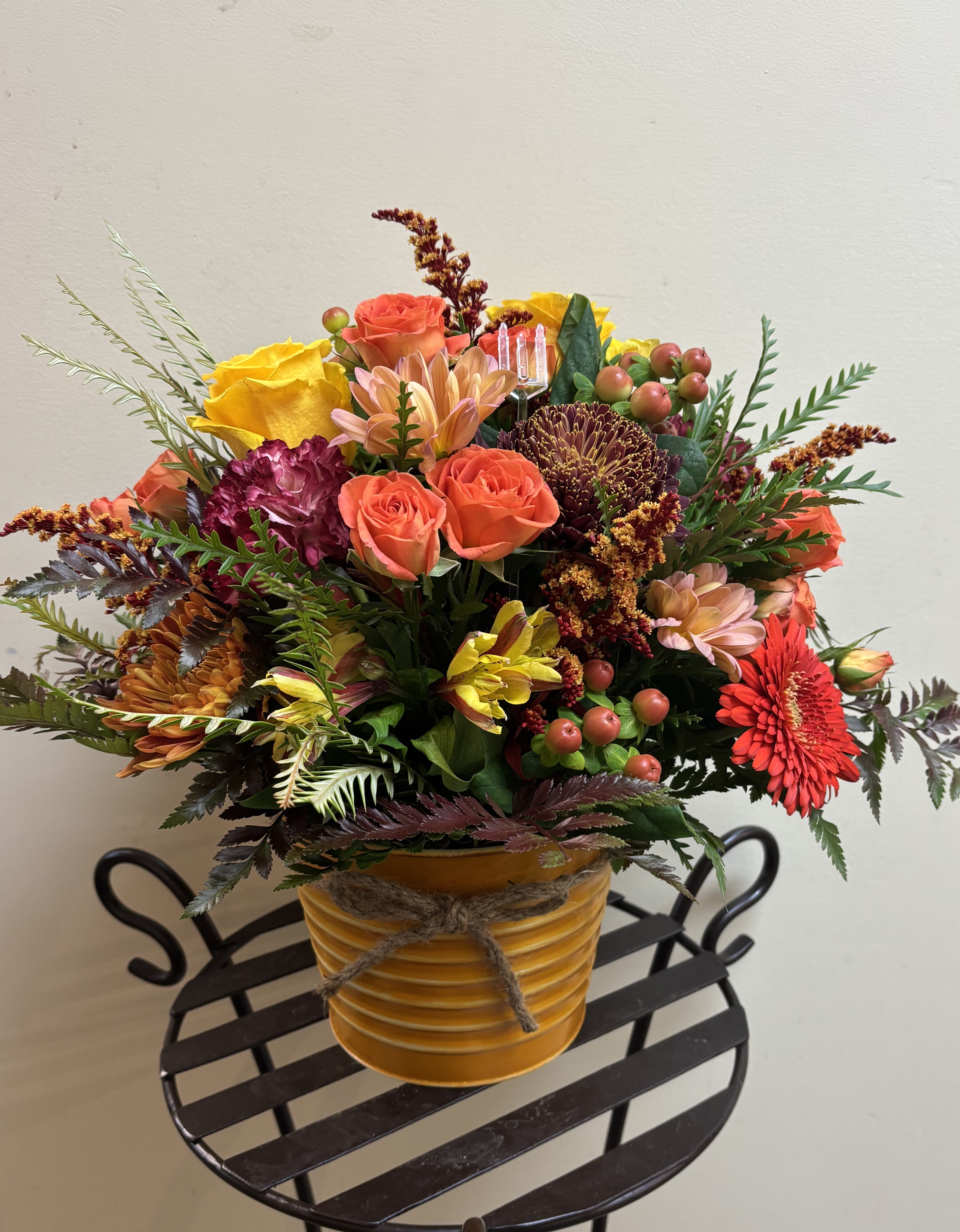 Mixed bouquet in a yellow ribbed pot with orange and yellow blooms