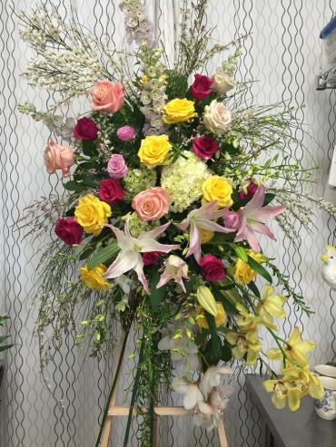 Tall floral spray with roses and lilies in pink, yellow, and white