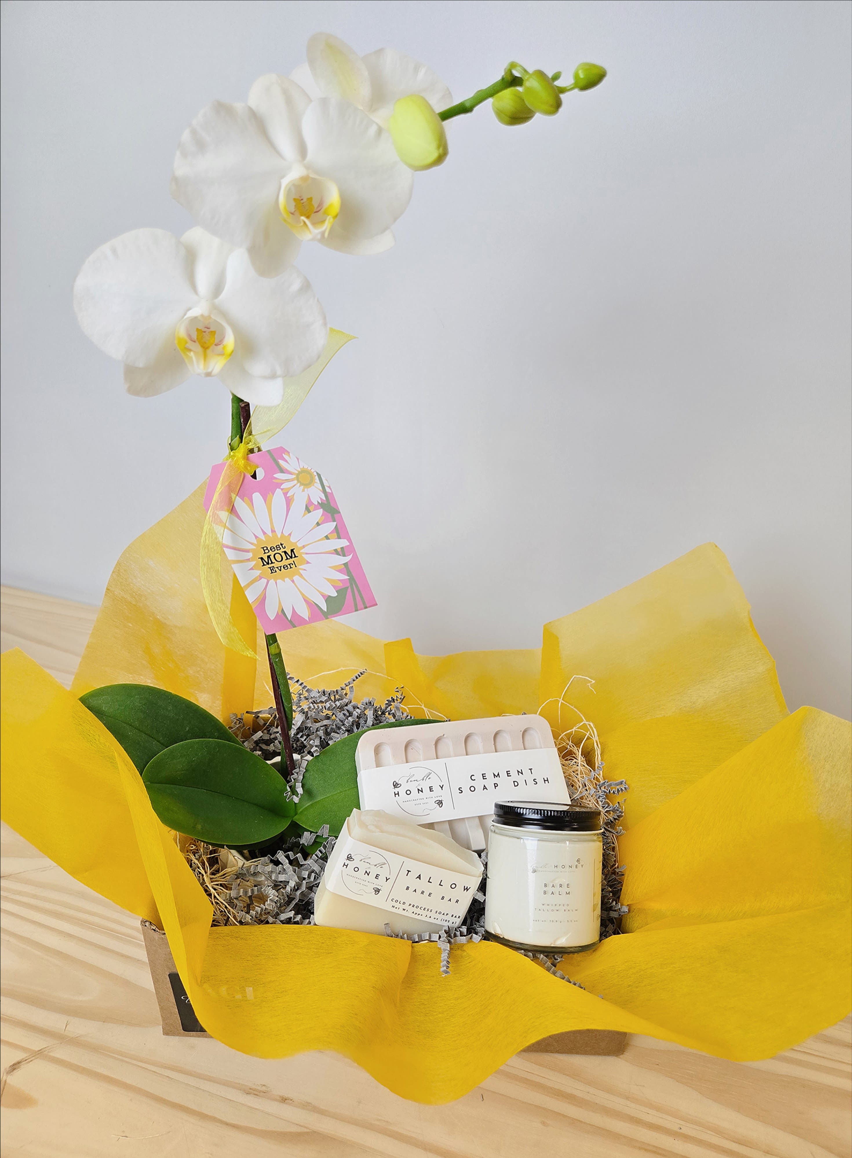 White orchid stem in a gift basket with soap and a candle