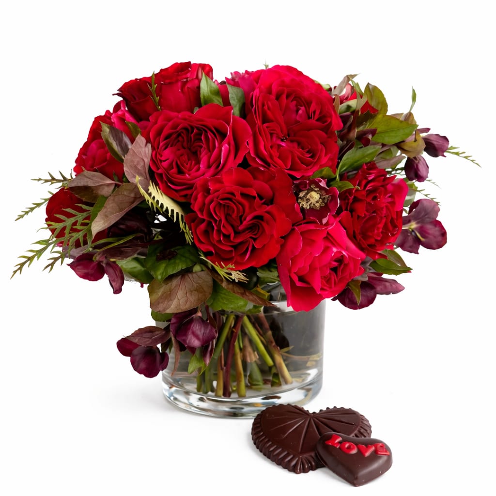 Red rose bouquet in a glass vase with heart-shaped chocolates