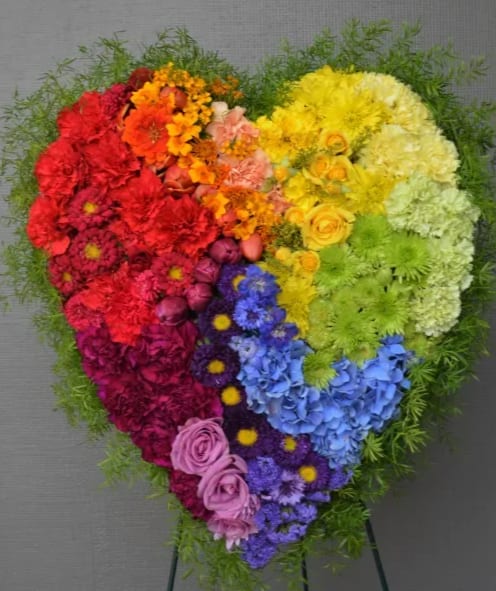 Heart-shaped rainbow floral arrangement on a stand