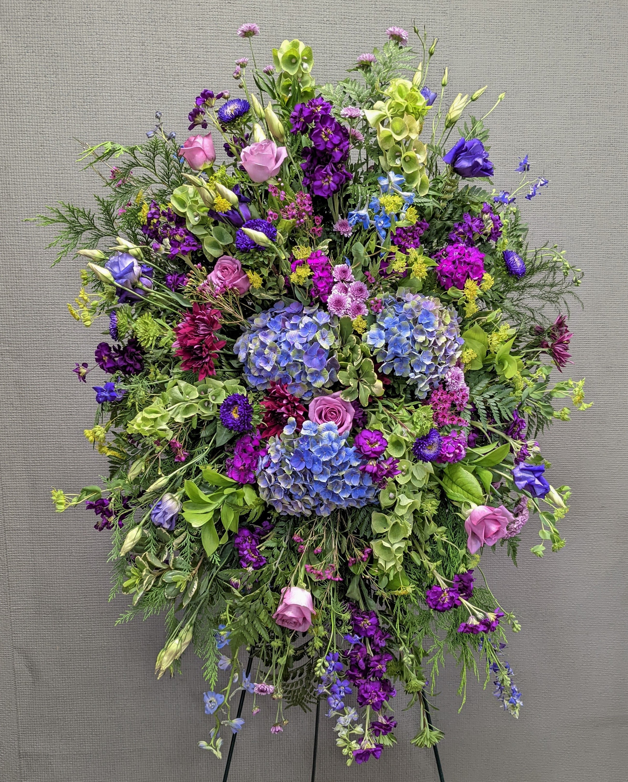 Large standing floral spray with purple, pink, blue, and green blooms