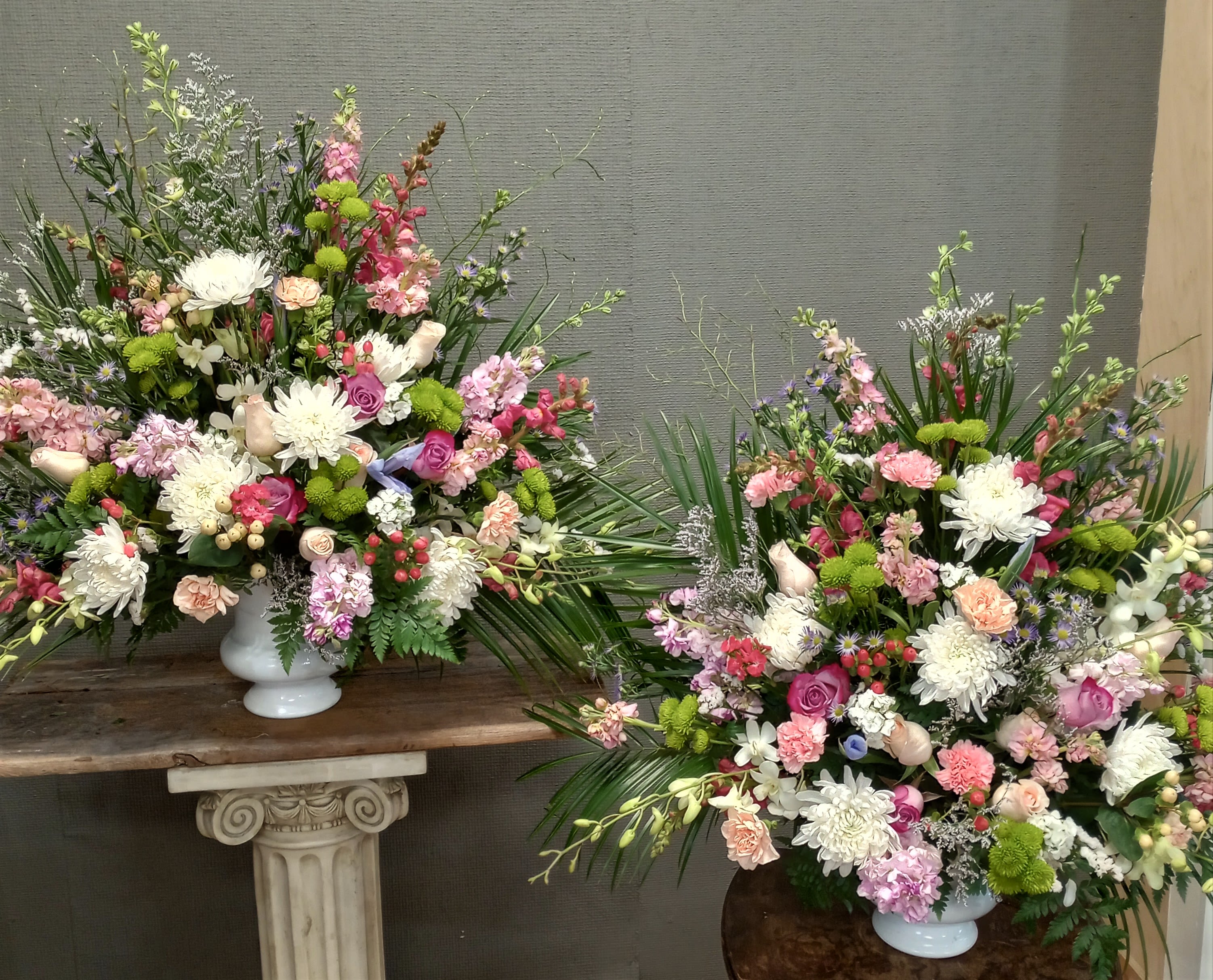 Two large mixed flower arrangements in white urns