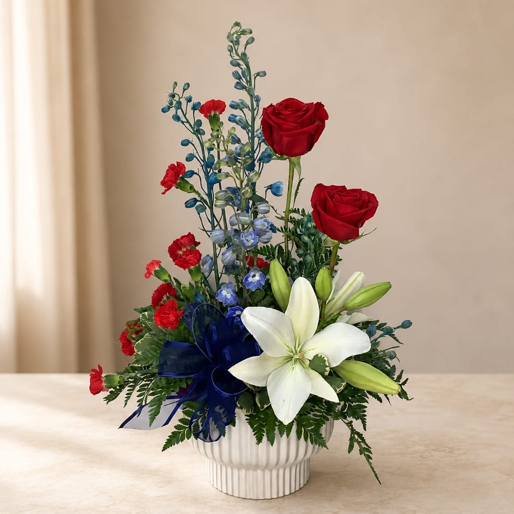 Red roses and white lilies in a white vase with a blue ribbon