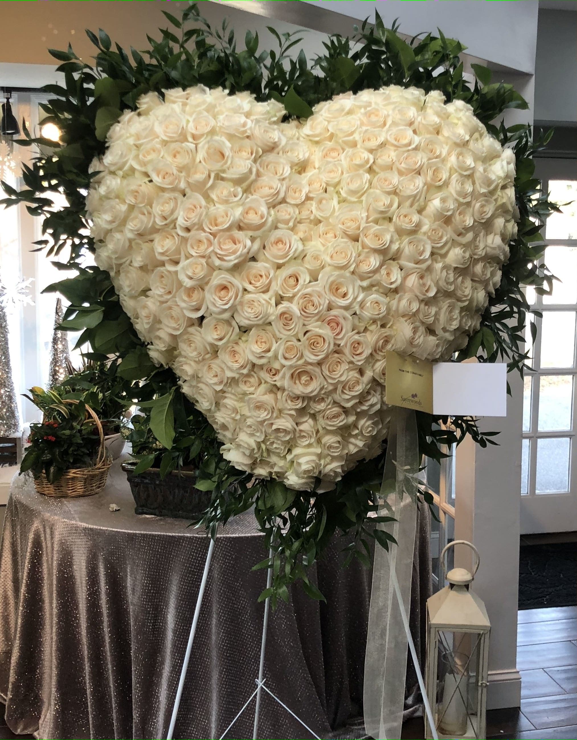 Heart-shaped arrangement of cream roses with dark greenery