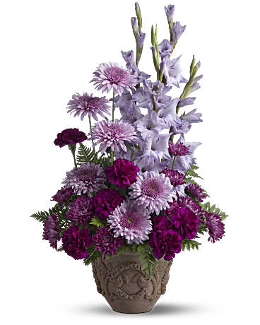 Purple and lavender mixed flower arrangement in a carved vase