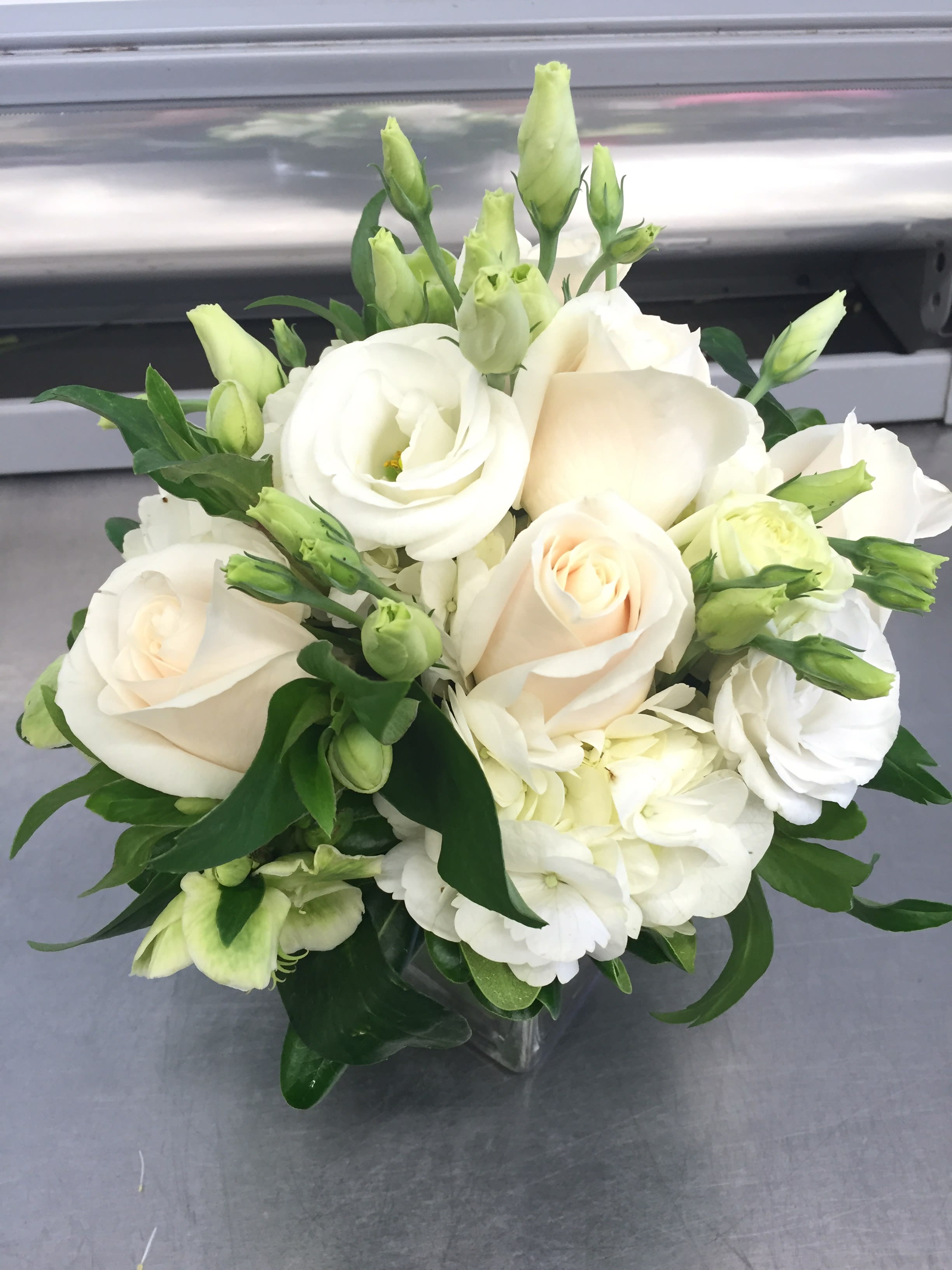 White roses and pale green lisianthus in a clear glass vase