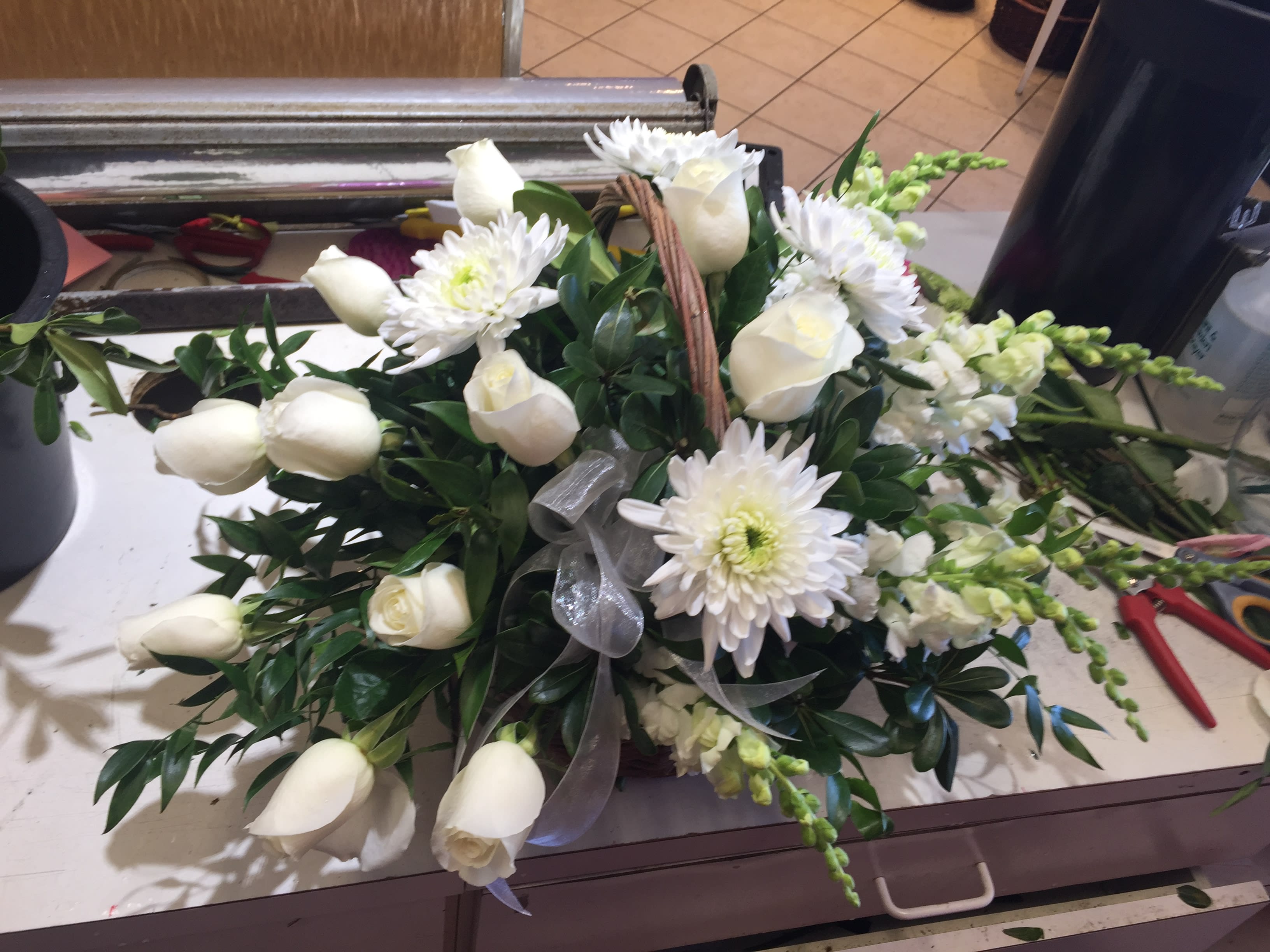 White roses and daisies arranged with greenery in a basket