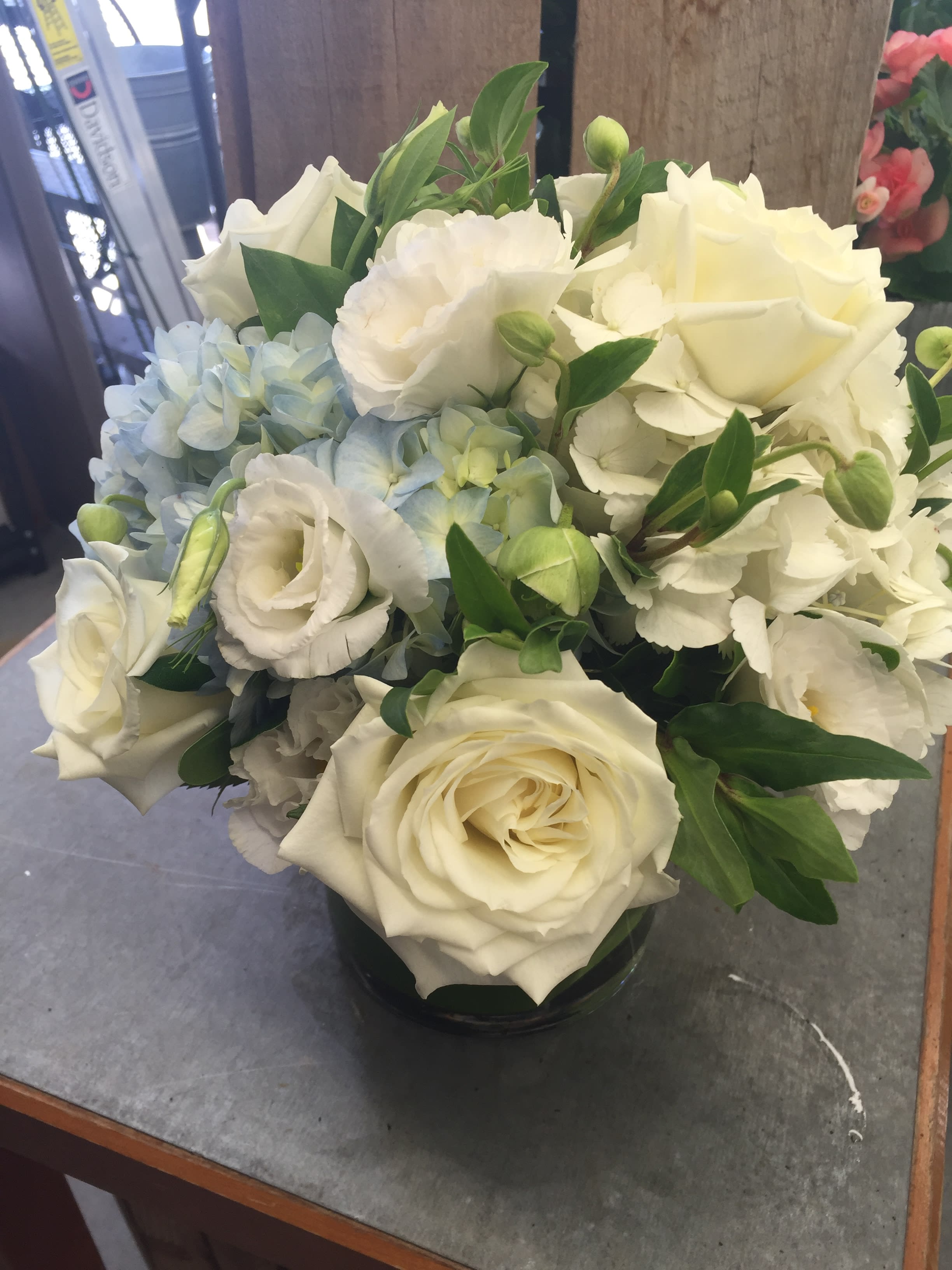 White roses and pale blue hydrangeas in a glass vase