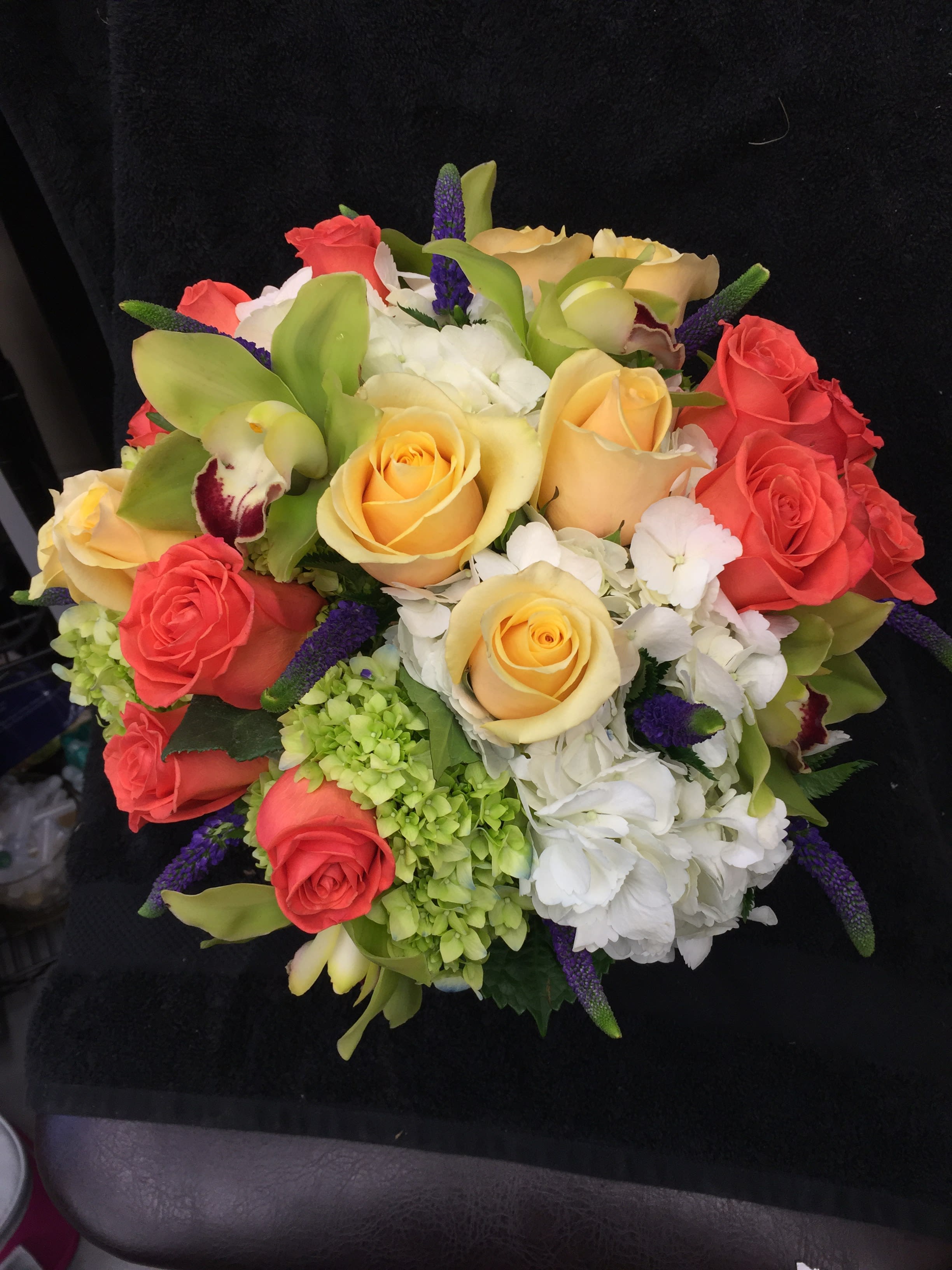 Bouquet of coral and yellow roses with white hydrangeas and purple accents