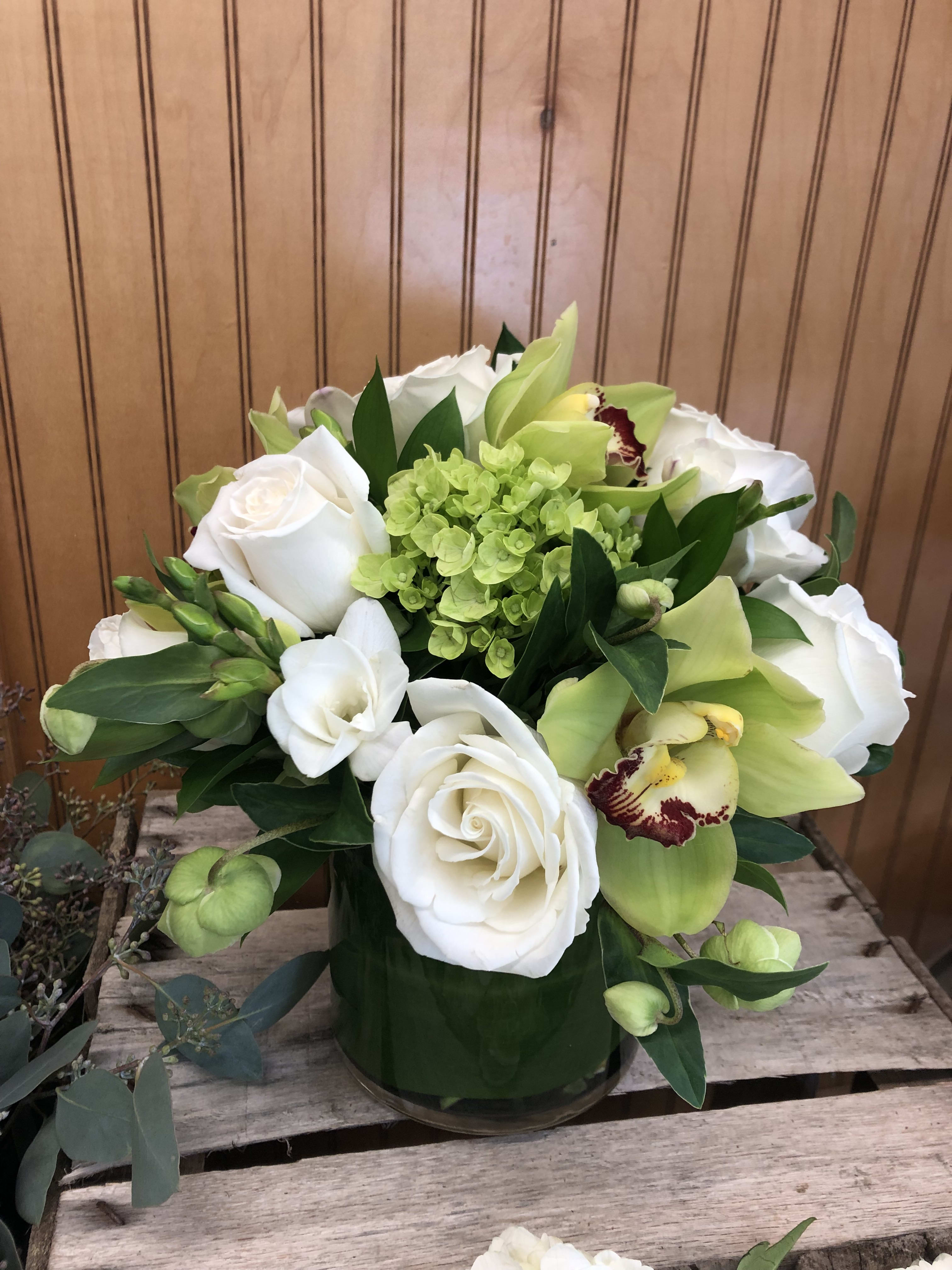 White roses and green orchids in a glass vase