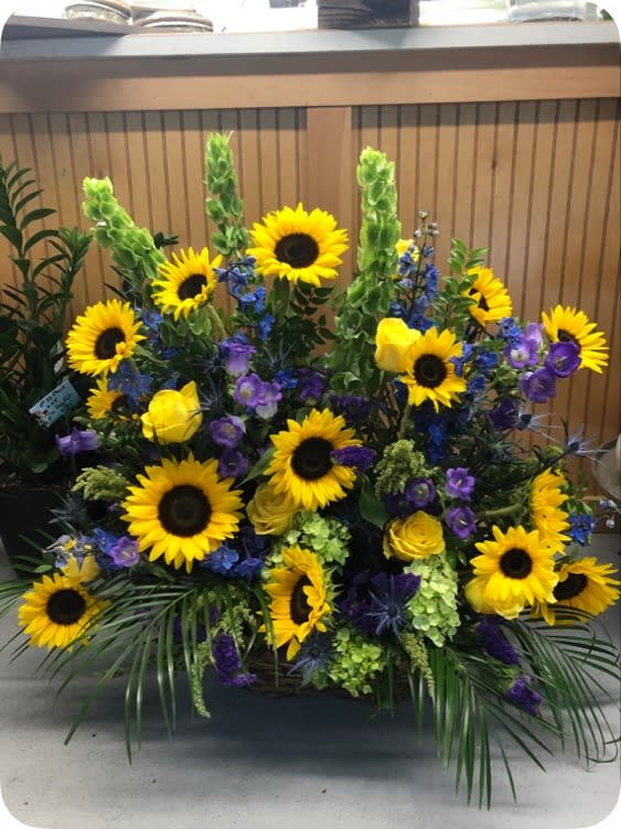 Large floral arrangement with sunflowers, yellow roses, and purple flowers