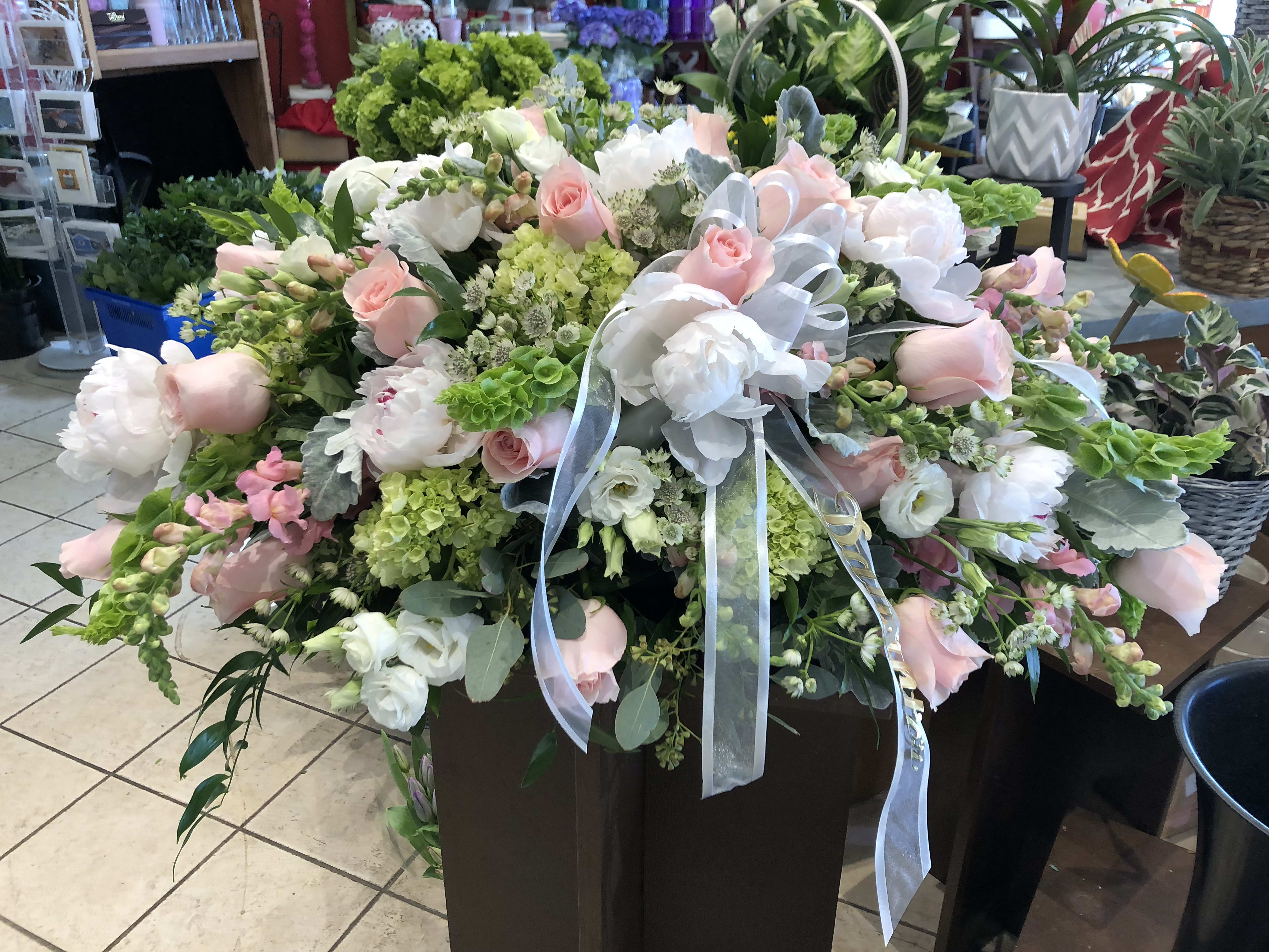 Large pastel floral arrangement with pink and white blooms and ribbon