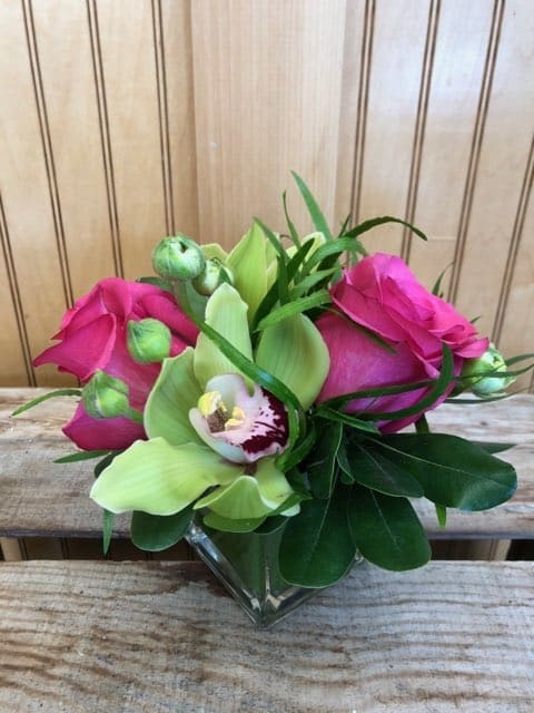 Pink roses and green orchids in a clear glass vase