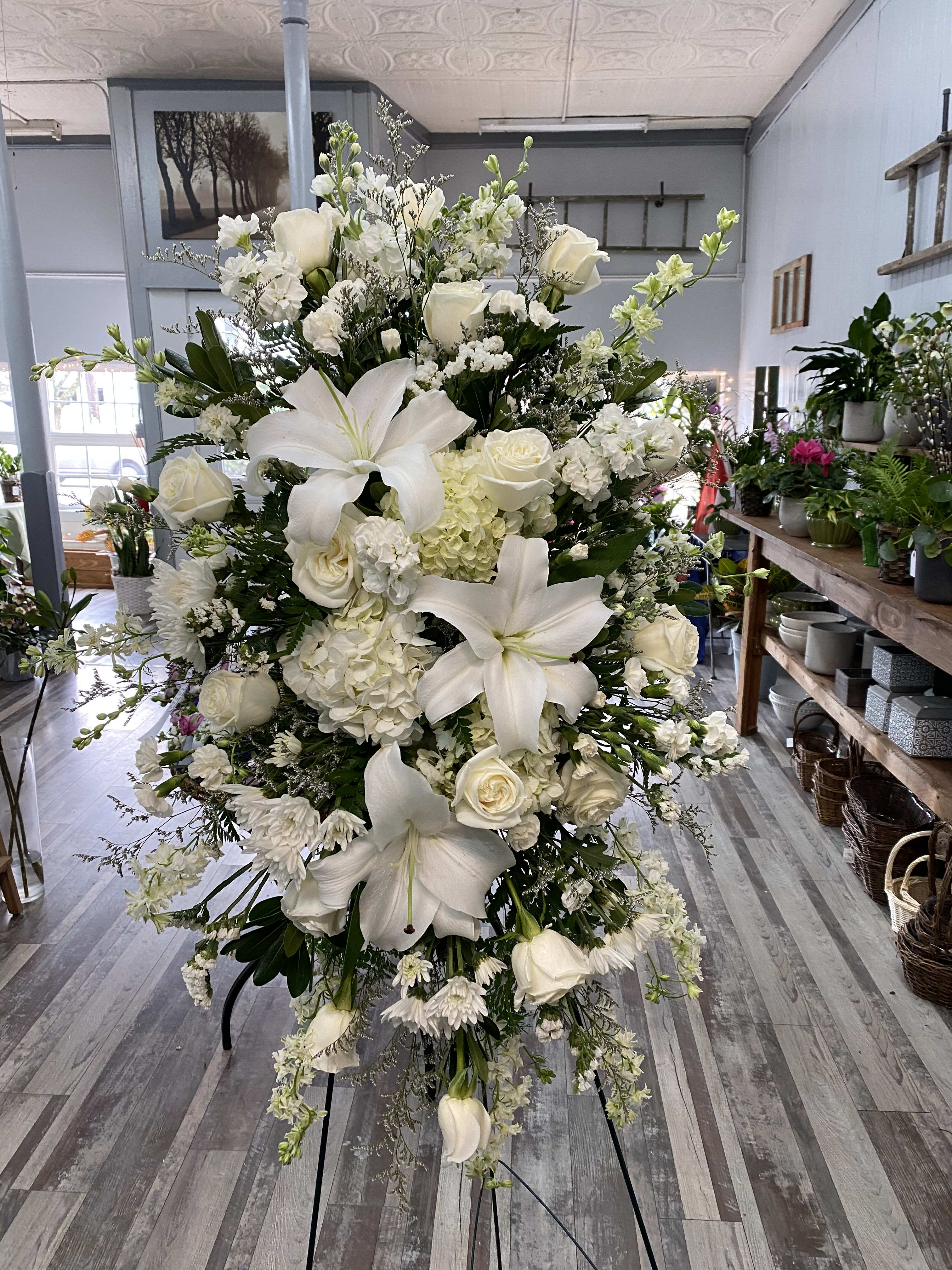 Large white floral standing spray with lilies, roses, and hydrangeas