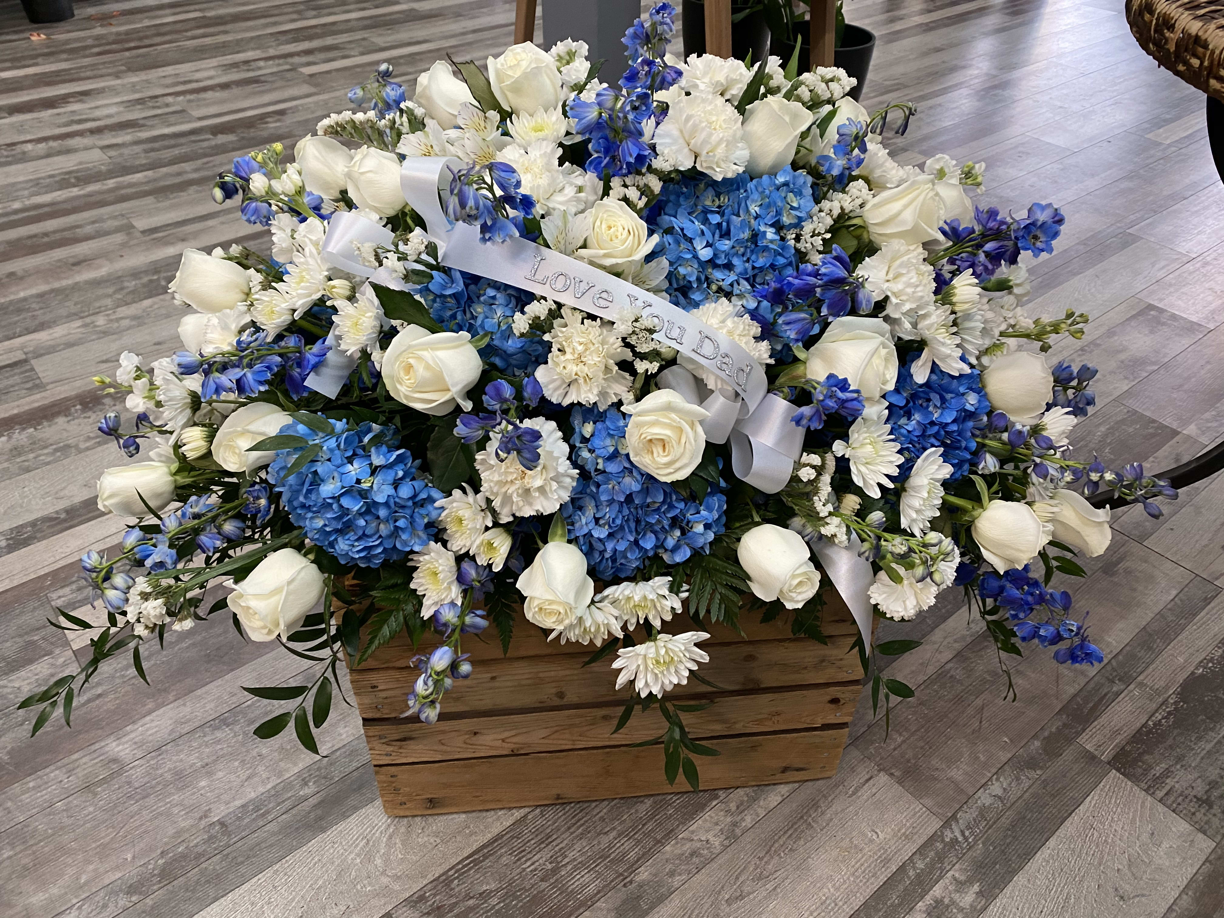 Blue and white floral arrangement in a wooden box with a ribbon