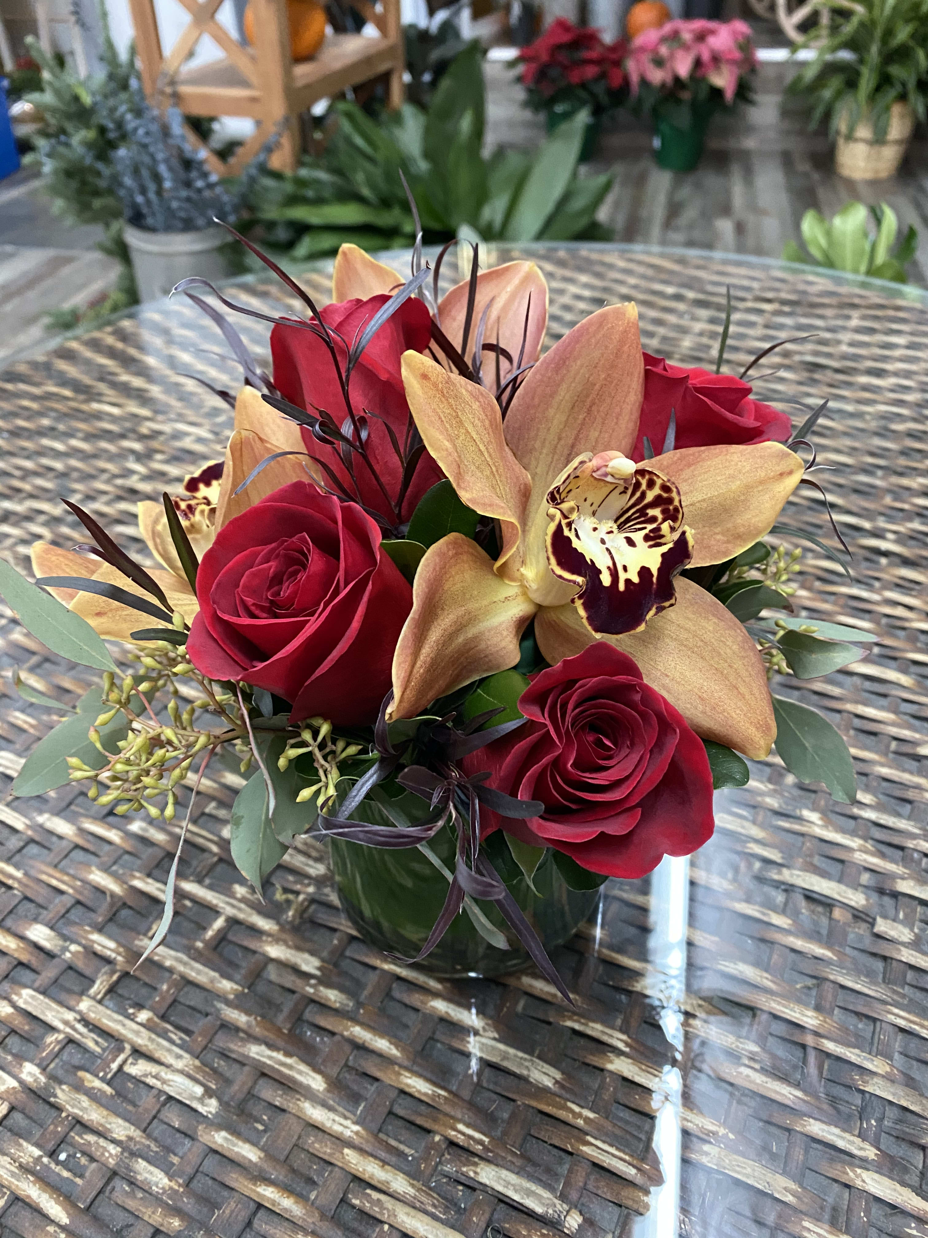 Red roses and orchids arranged in a glass vase