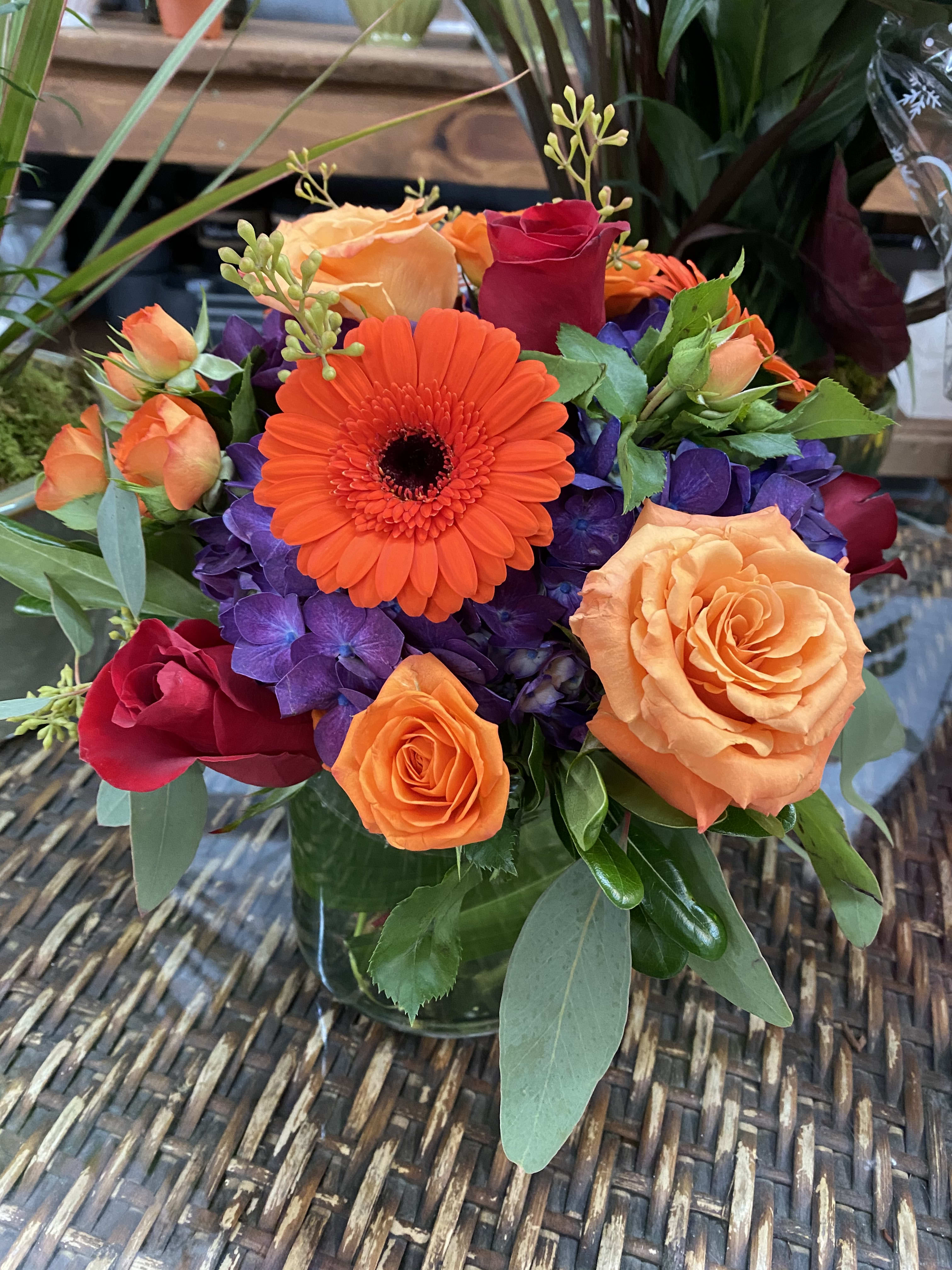 Orange gerbera and roses in a glass vase