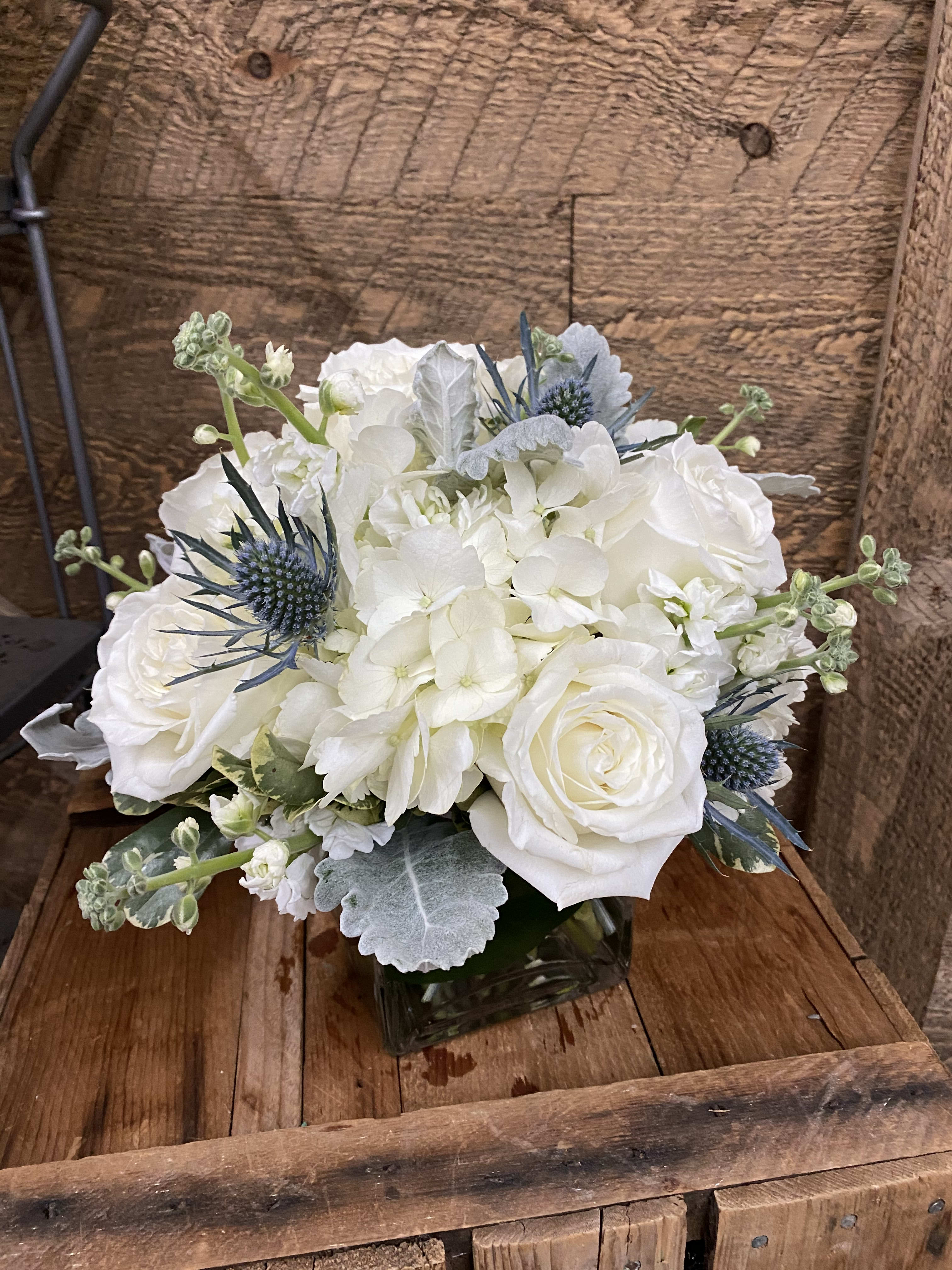 White roses and hydrangeas in a square glass vase