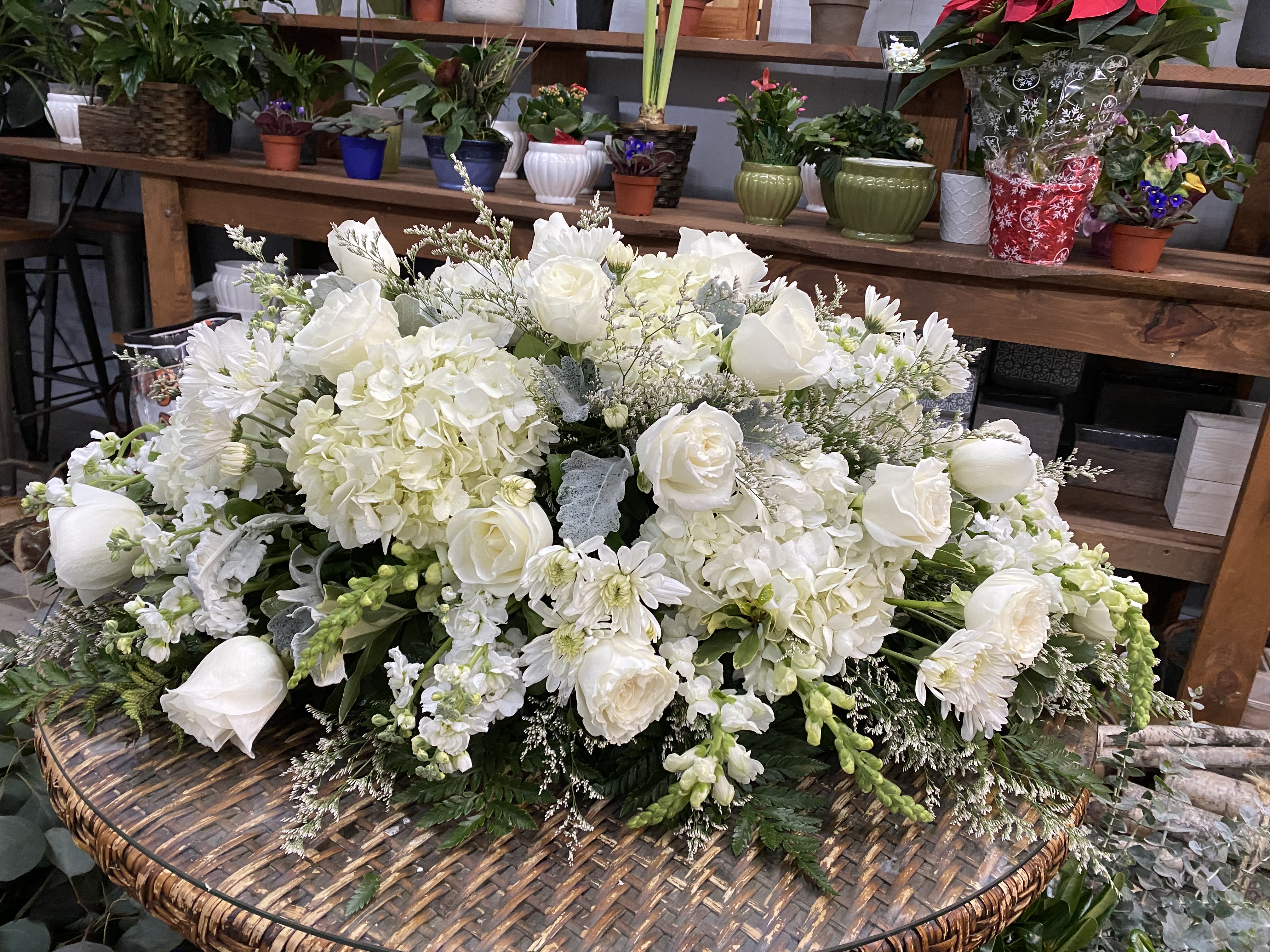 Large white floral arrangement with roses, hydrangeas, and daisies