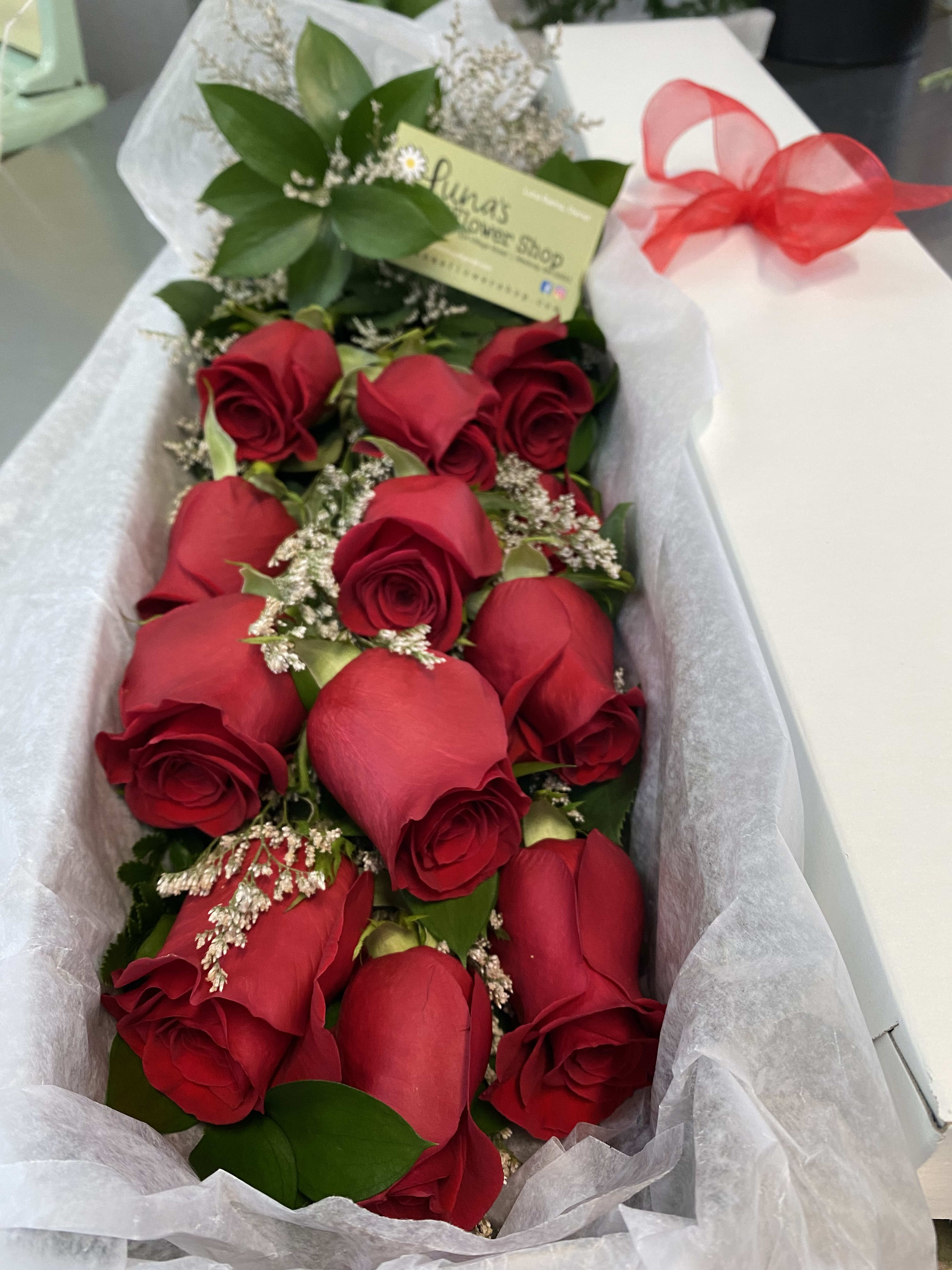 Bouquet of red roses wrapped in white paper with a red ribbon