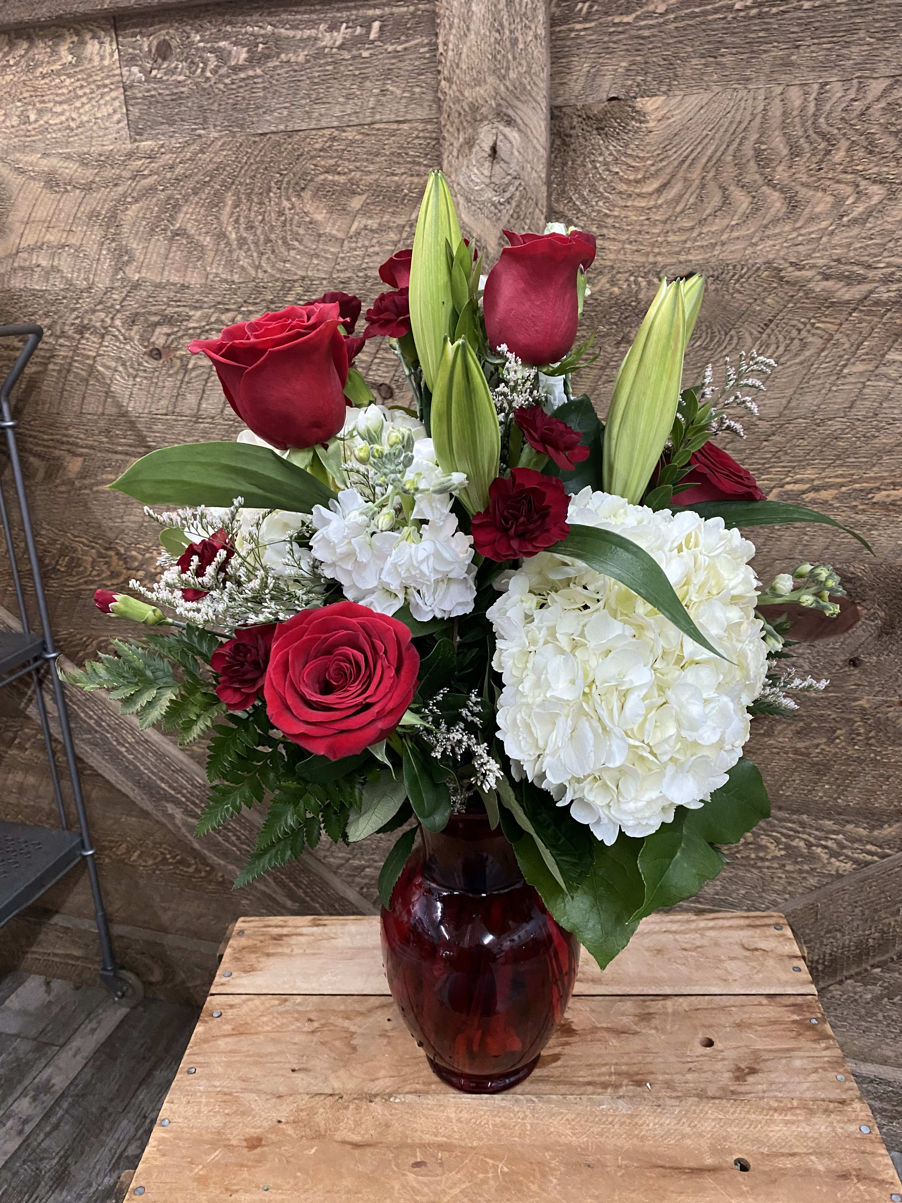 Red roses and white hydrangeas in a red glass vase