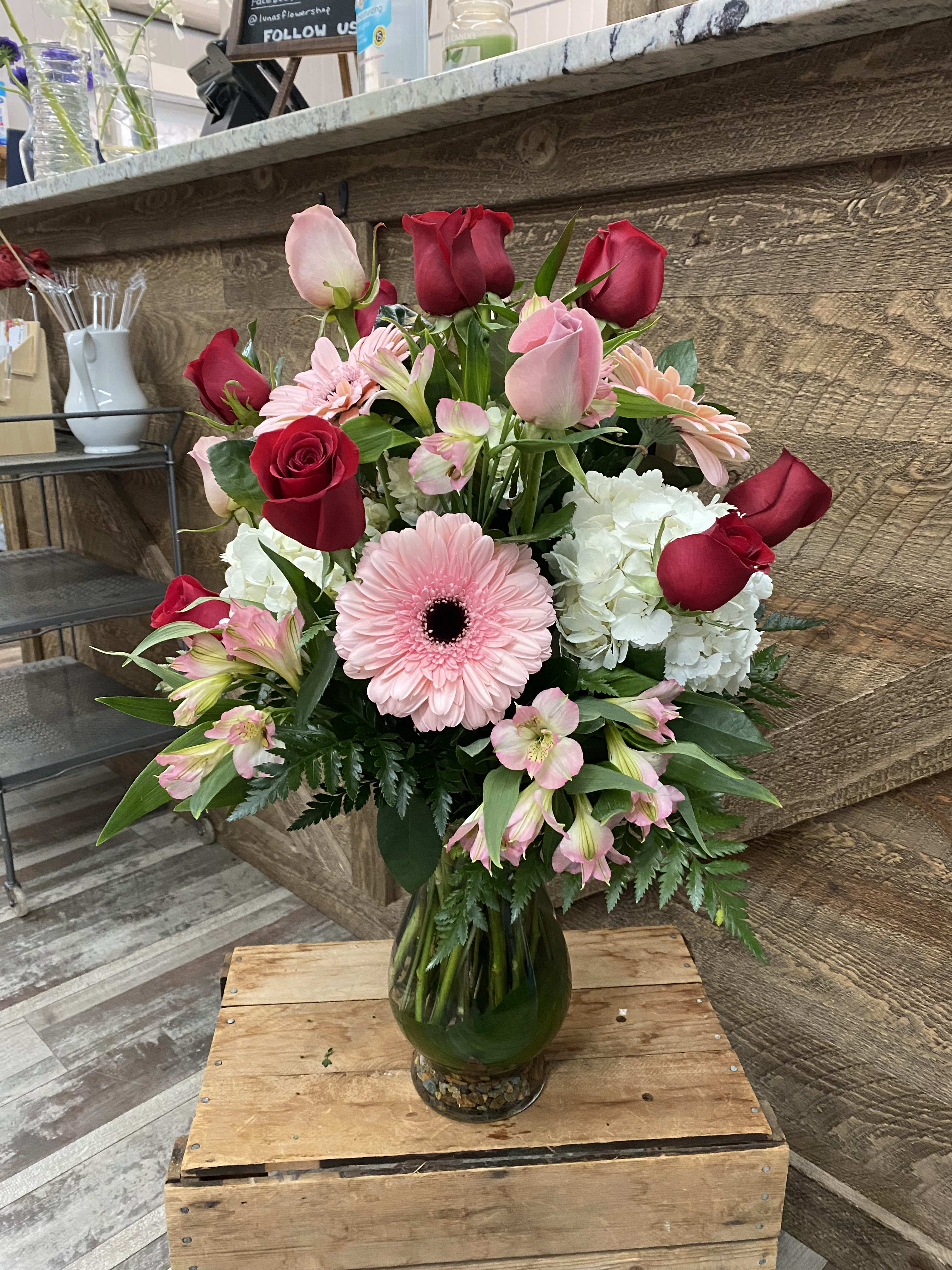 Bouquet of red and pink roses with a pink gerbera daisy in a glass vase