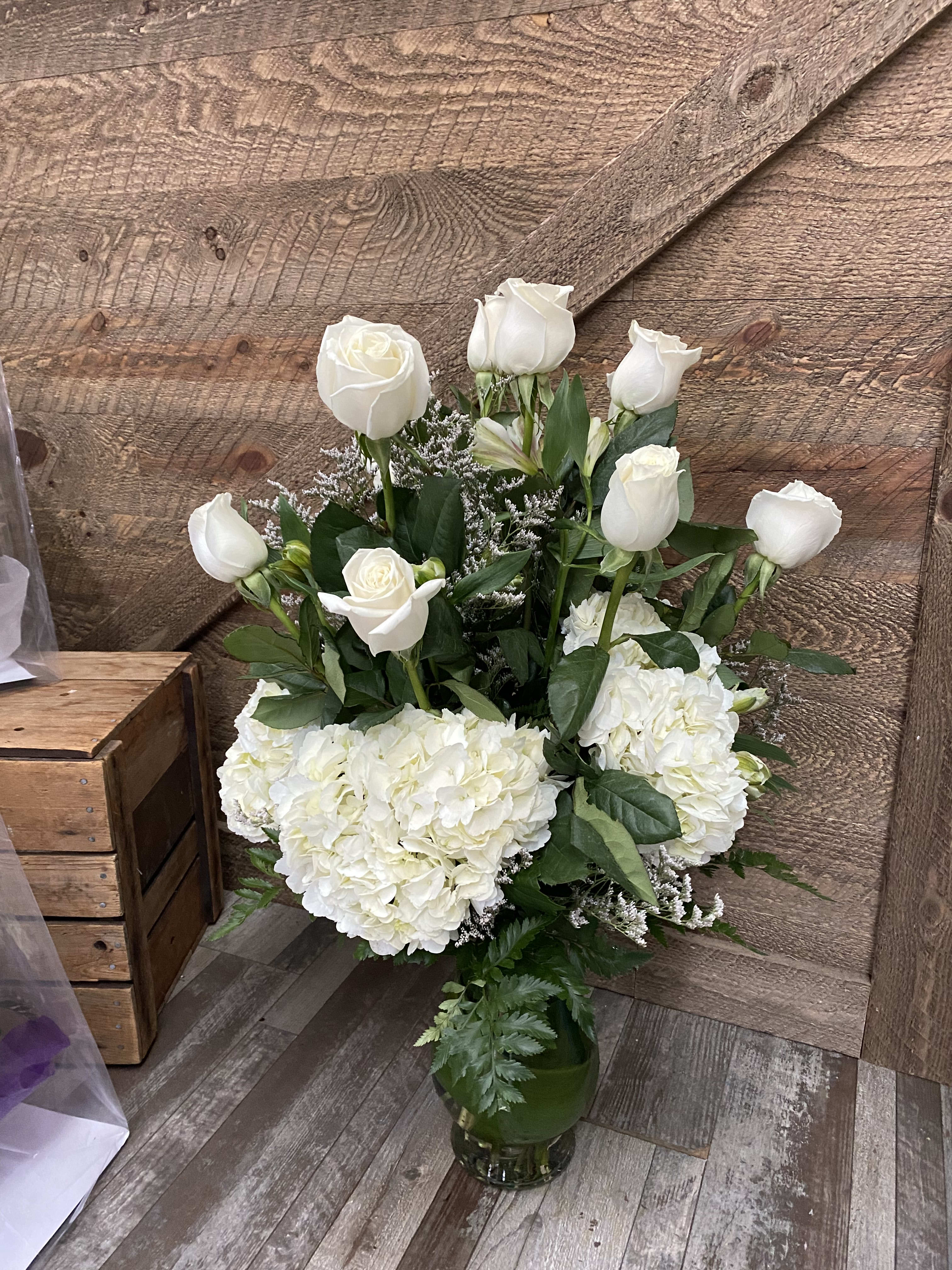 White roses and hydrangeas arranged in a glass vase