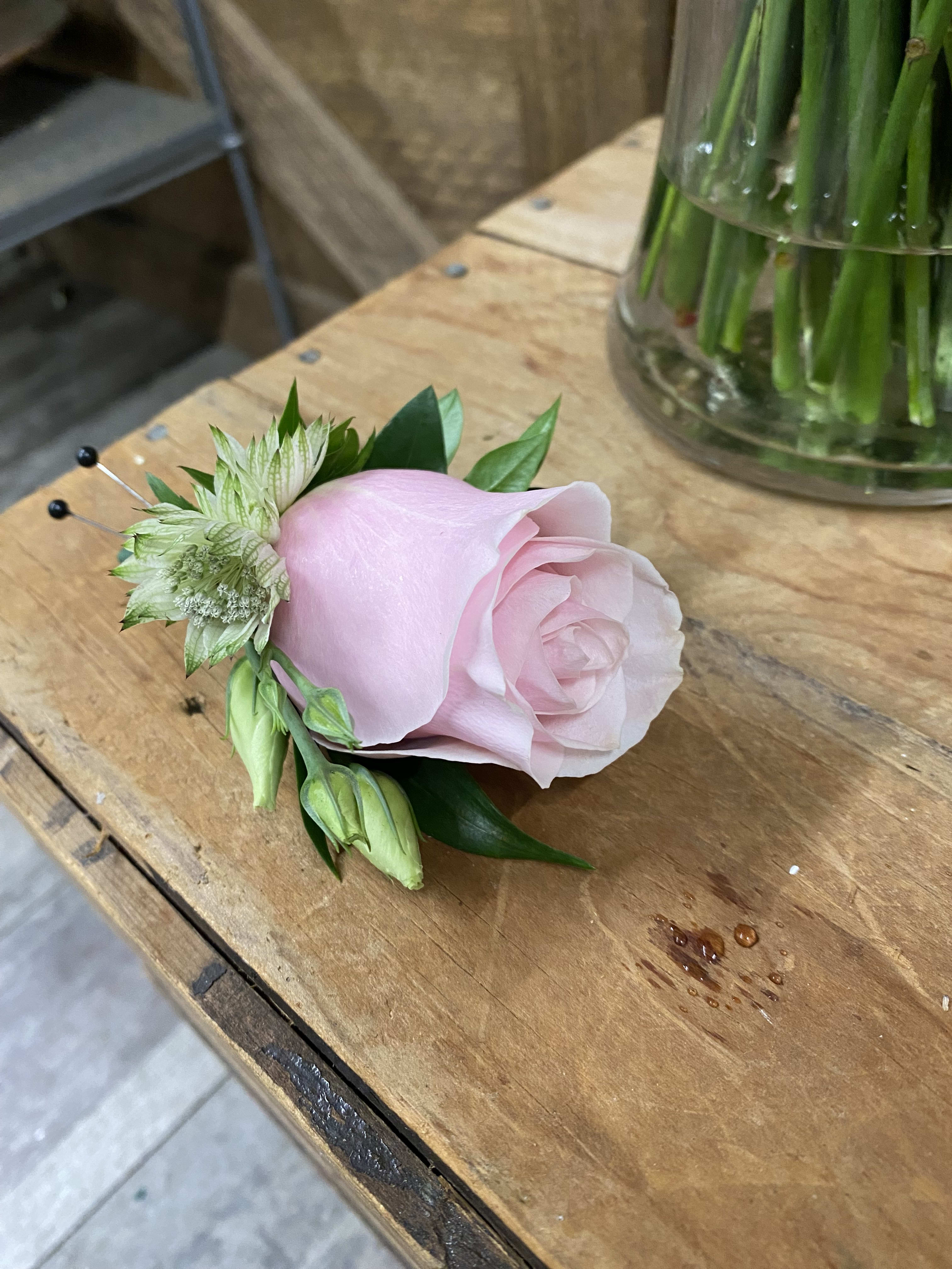 Single pale pink rose boutonniere with small white accent flowers