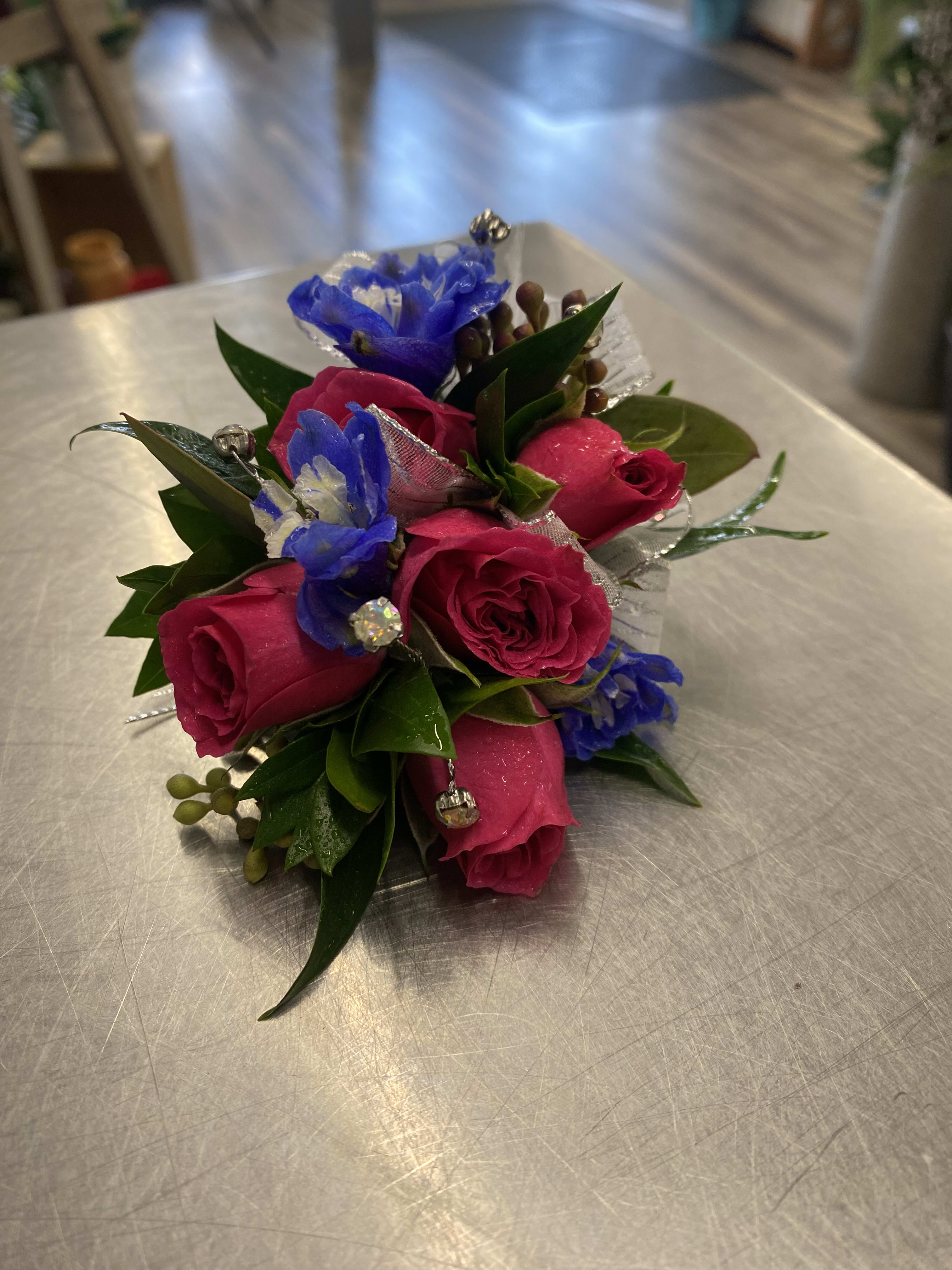 Small bouquet of pink roses and blue flowers with decorative accents